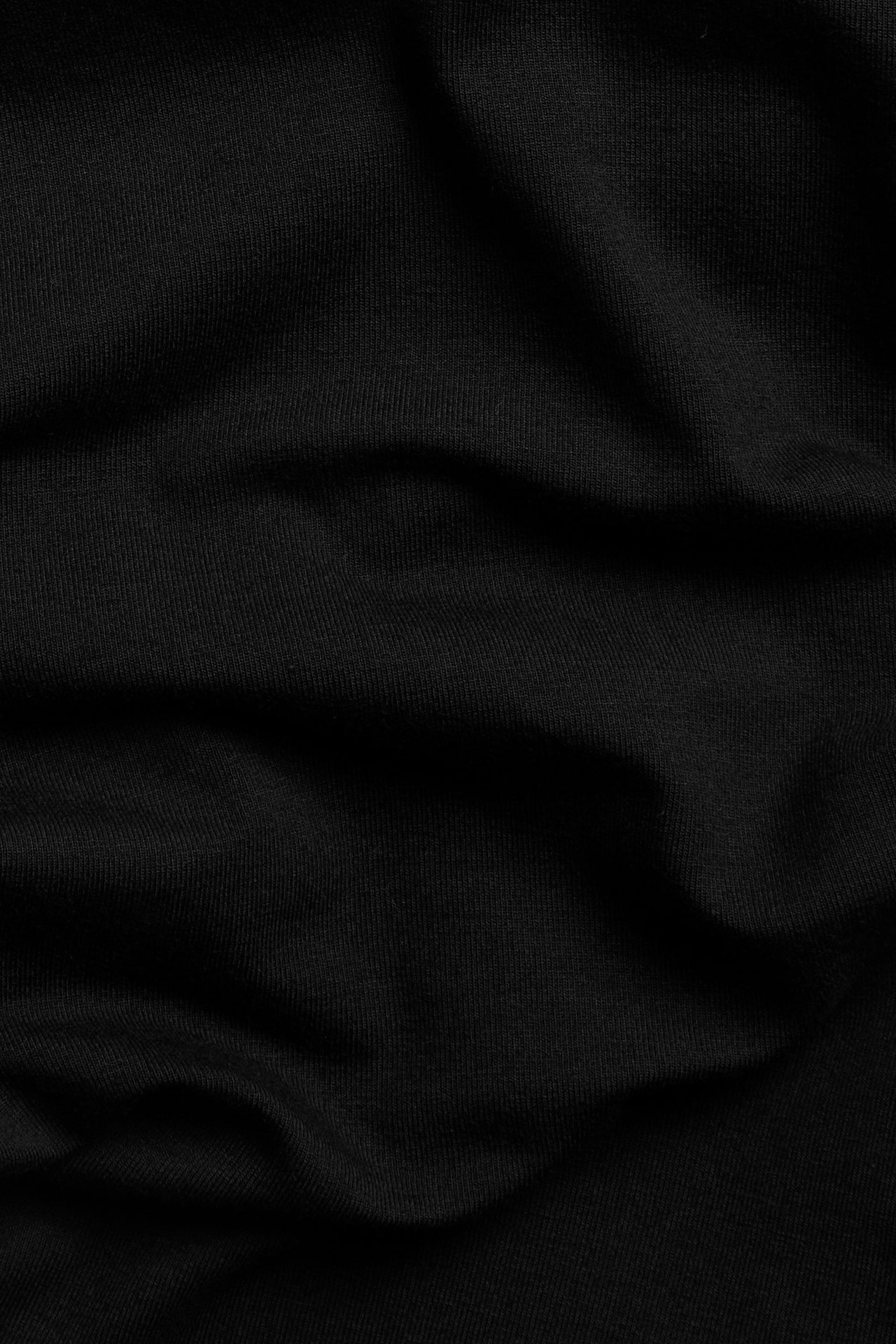 Zbliżenie na czarny, miękki materiał z mieszanki wiskozy z delikatnymi fałdami, przedstawiający legginsy flare.