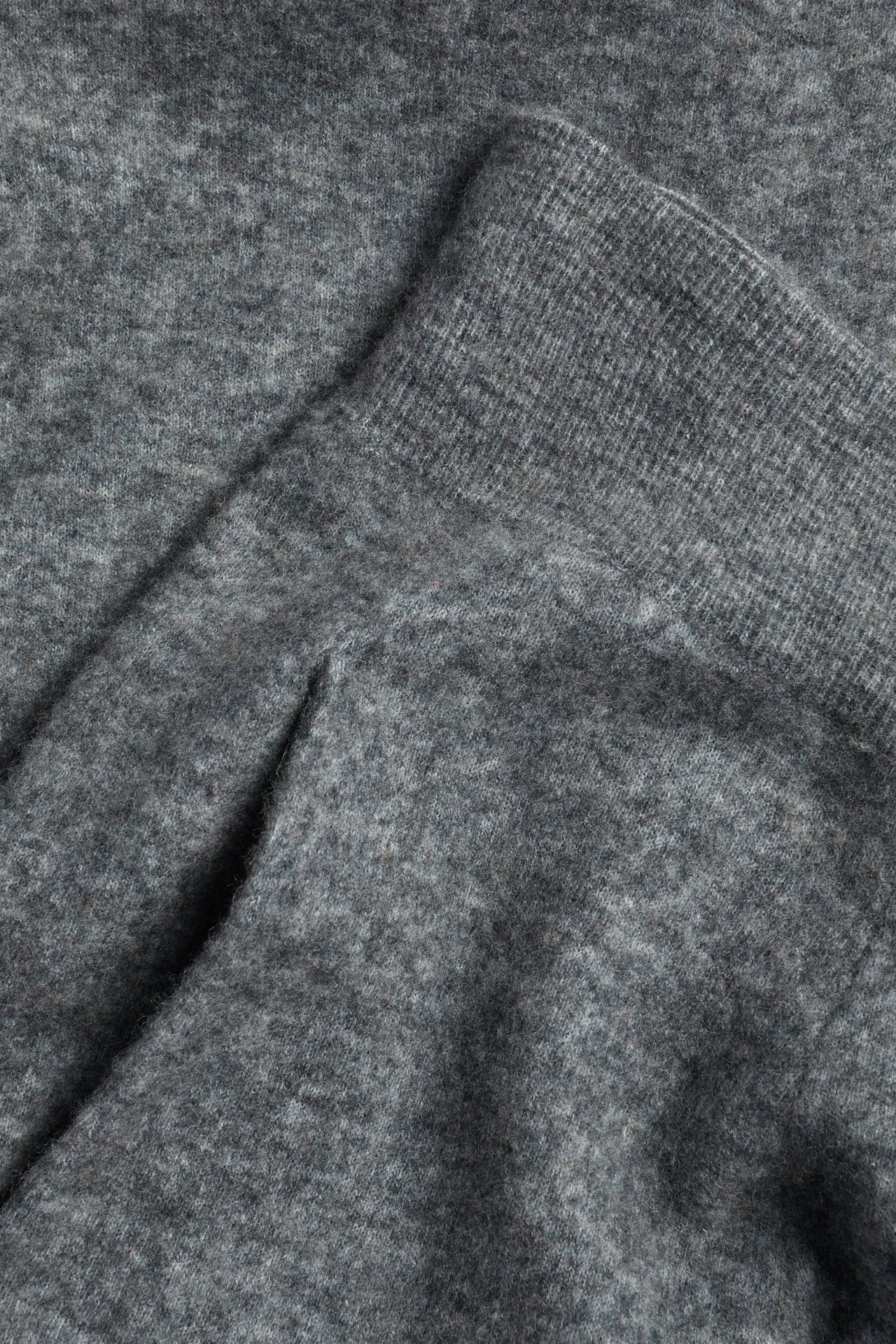Zbliżenie ciemnoszarych, drobno dzianych spodni barrel, ukazujące miękką teksturę i prążkowany brzeg.
