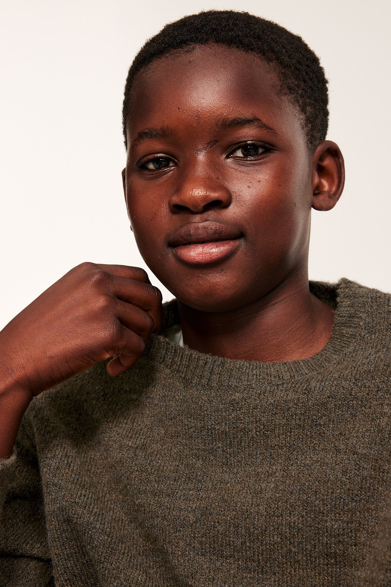 Lähikuva edestä lapsesta, yllään ruskea meleerattu neulepusero ribbineuleisella pyöreällä pääntiellä.