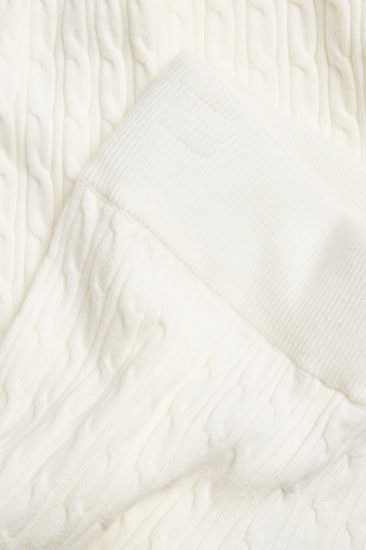 Zbliżenie na off-white spodnie z warkoczowym splotem i prążkowanym elastycznym pasem.