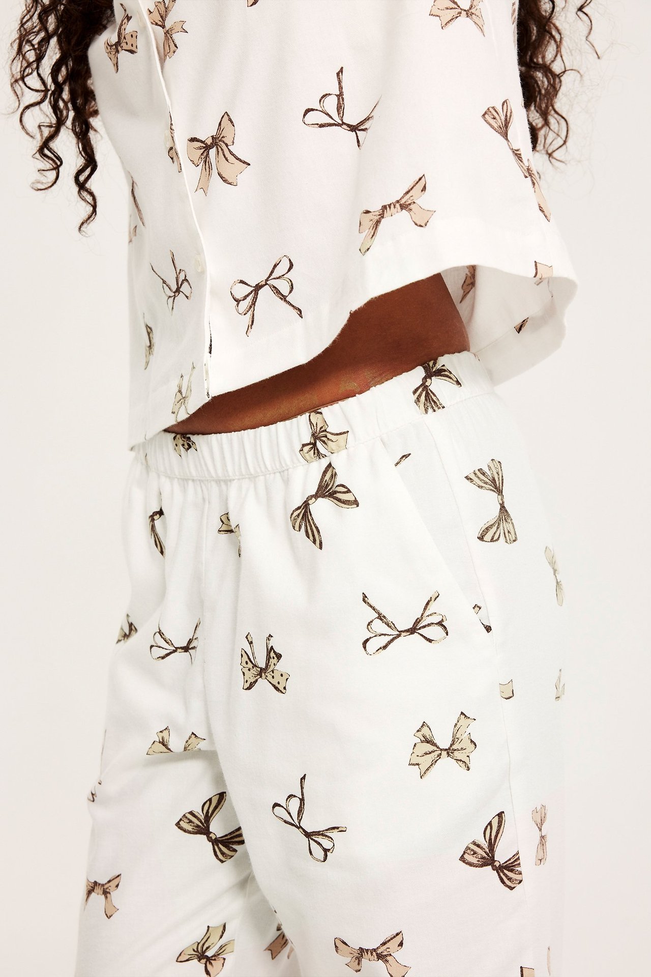 Lähikuva, sivukuva naisesta valkoisessa flanellipyjamassa ruskealla rusettikuviolla.