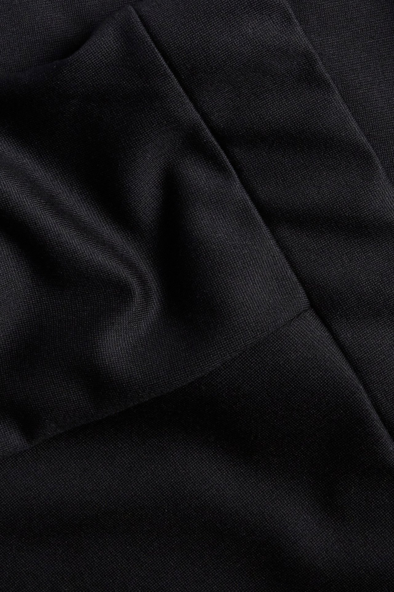 Zbliżenie czarnej, jednolitej spódnicy skater z mieszanki wiskozy z widocznymi fałdami i szwami.