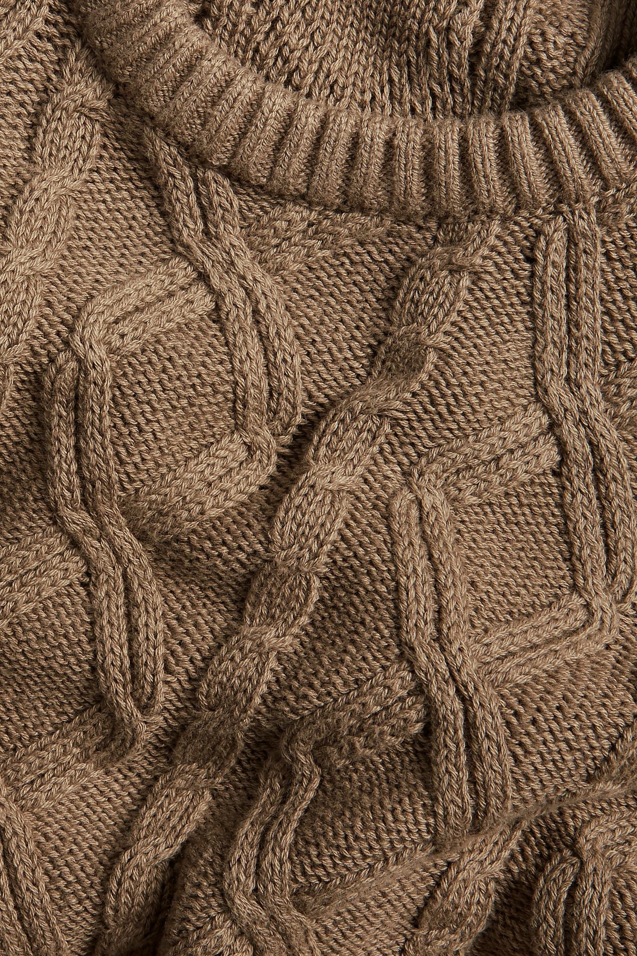 Zbliżenie brązowego swetra z bawełny o warkoczowym splocie z prążkowanym dekoltem.