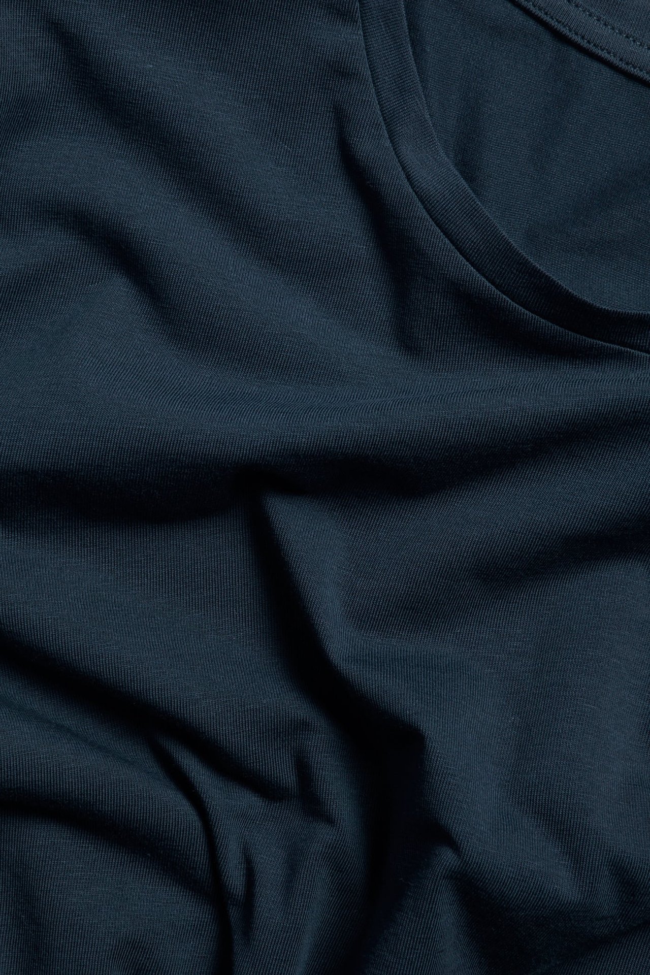 Zbliżenie na granatowy, jednolity bawełniany t-shirt z okrągłym dekoltem.