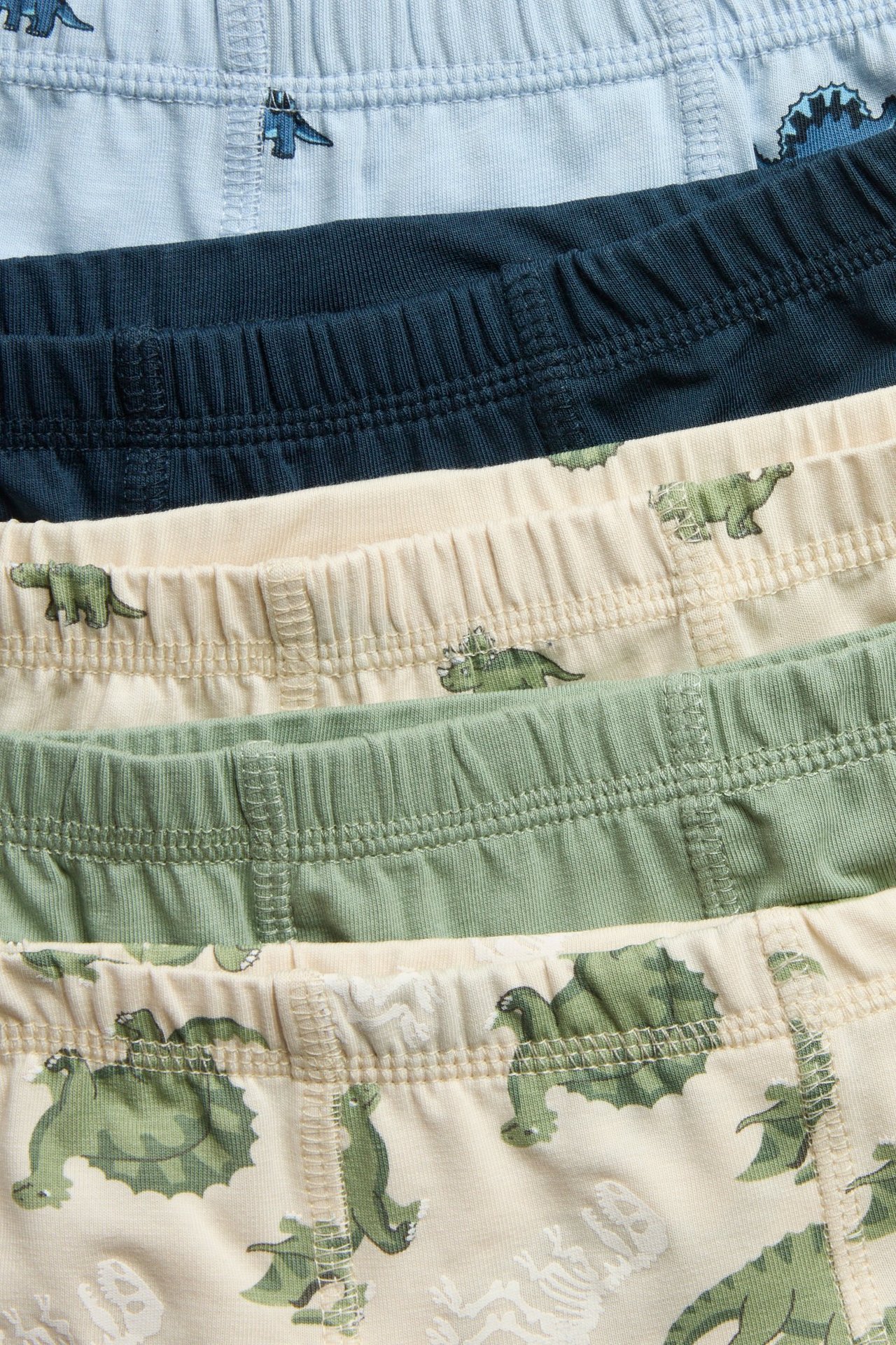 Viisi lasten bokseria: vaaleansininen, tummansininen, vaaleanbeige, vaaleanvihreä. Joissakin dinosauruskuvio.