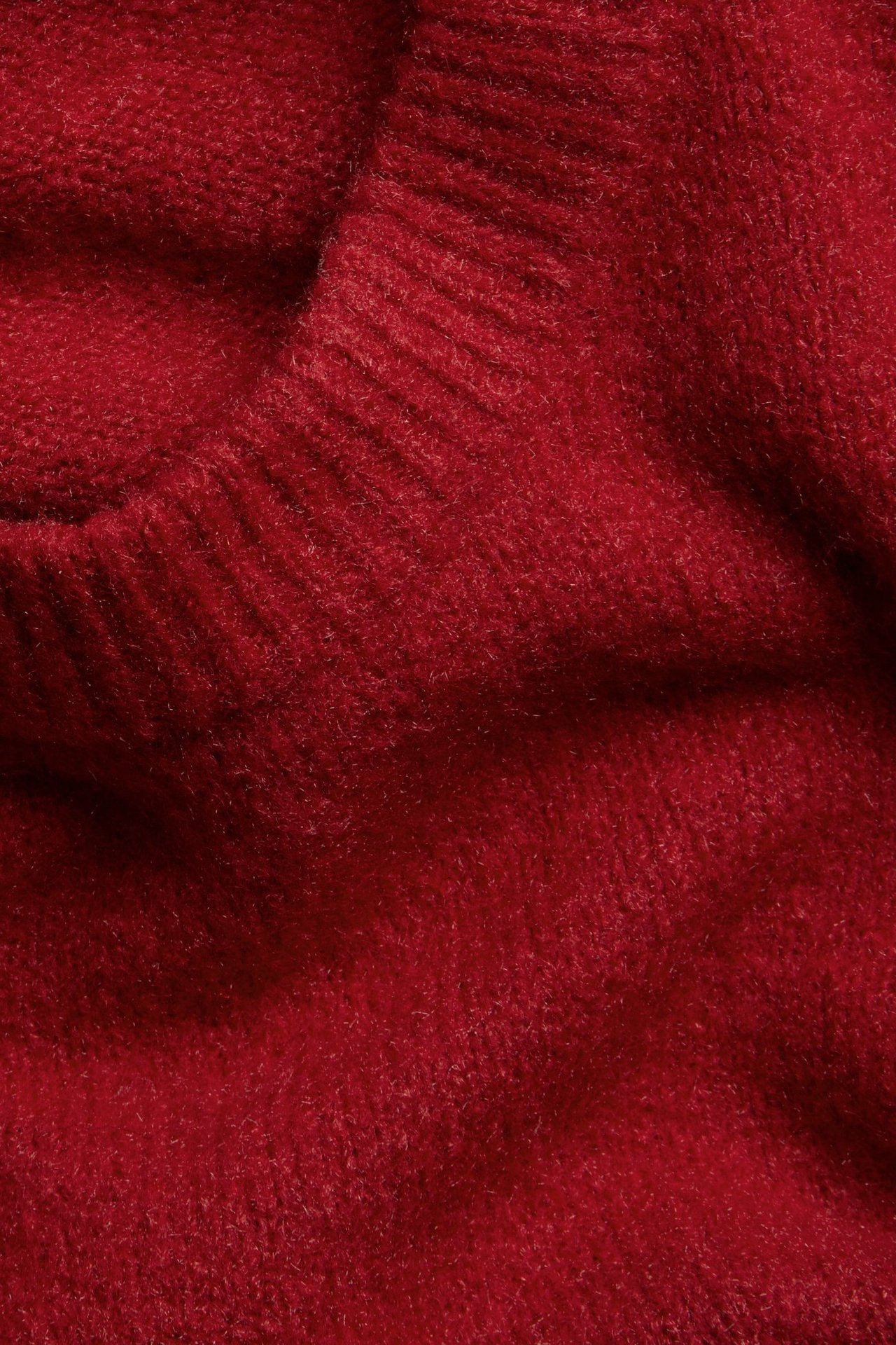 Närbild på det mjuka, röda, finstickade tyget av en kortärmad t-shirt.