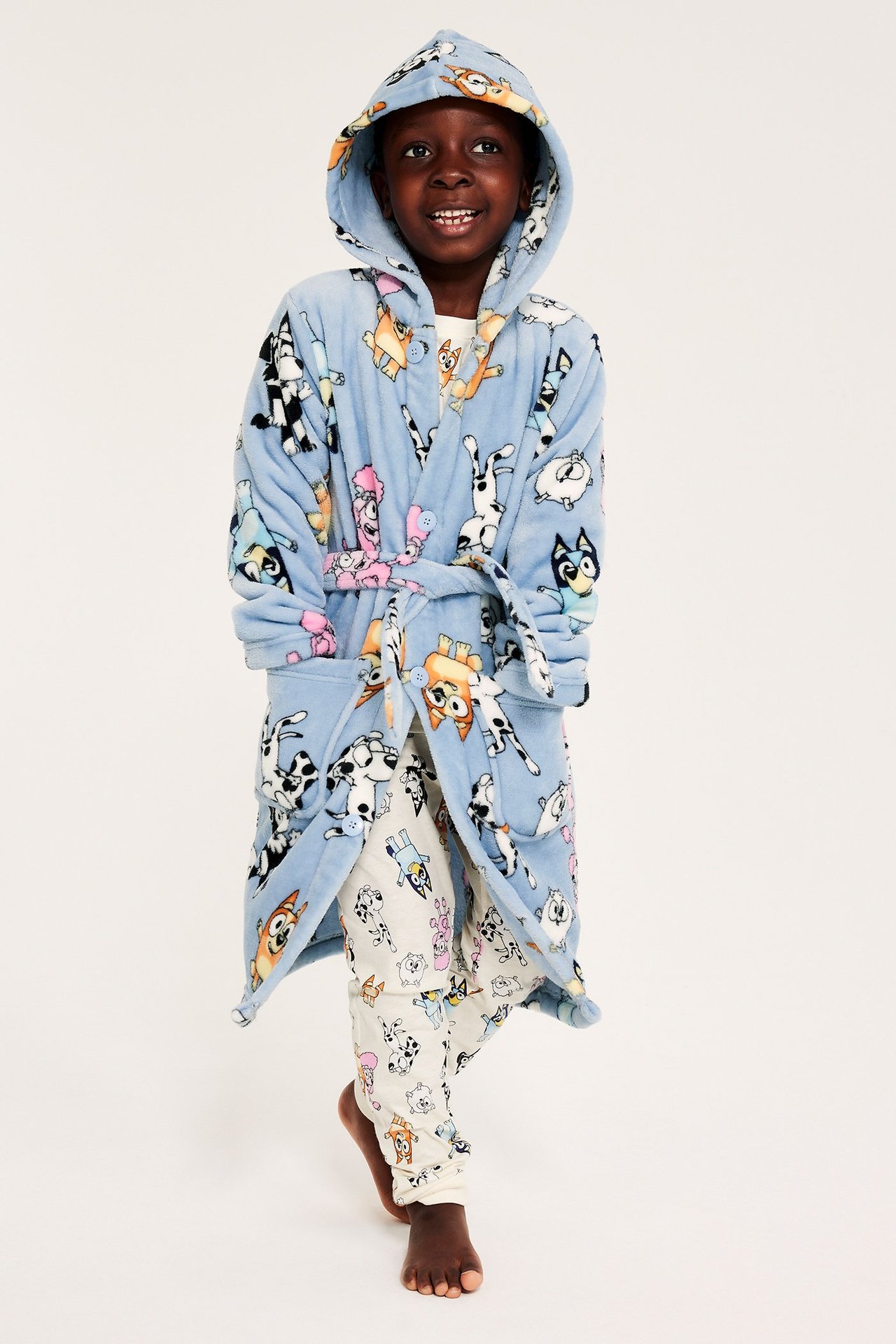 Lapsi sinisessä fleecemorgonrökissä Bluey-kuvalla, huppu, napit, kaksi taskua ja vyö.