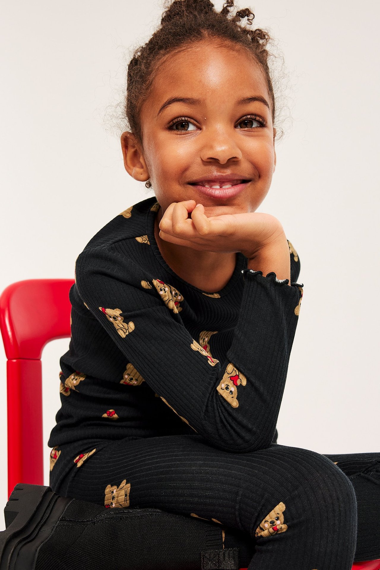 Barnmodell i svart ribbad topp med nallebjörnar, långärmad, over svart t-shirt.