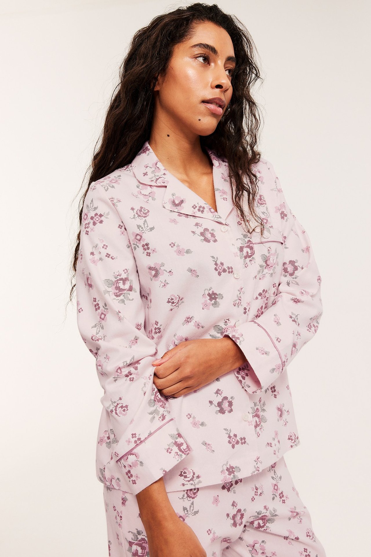 Zbliżenie kobiety w różowej piżamie z bawełnianej flaneli we wzory, z detalami z lamówki.