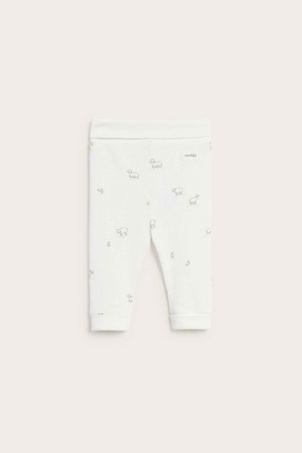 Frontvy av offwhite baby-leggings i våfflad struktur med subtilt lammönster och muddar.