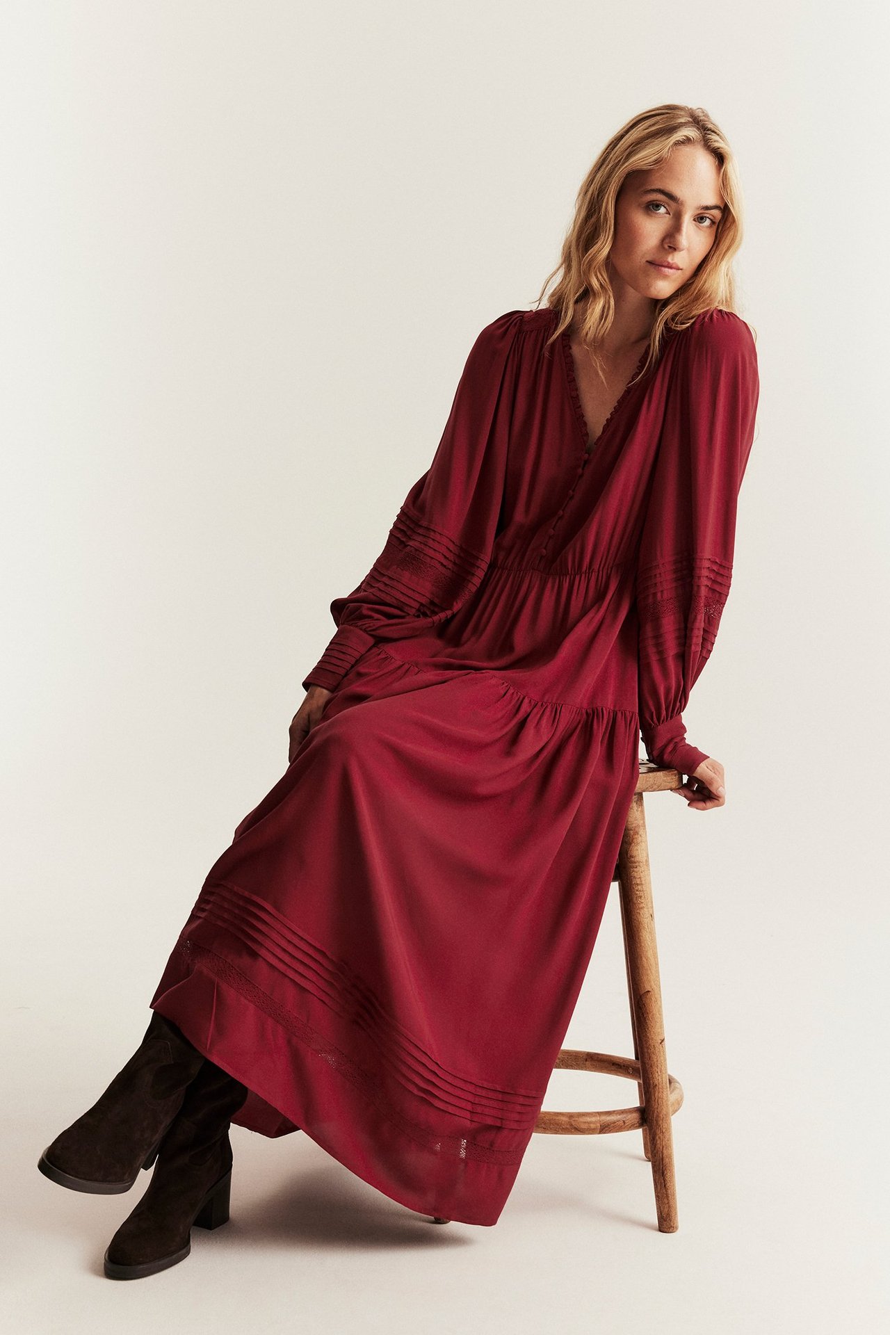 Rød viskosekjole med blonder og elastisk midje, kvinne sitter på krakk.