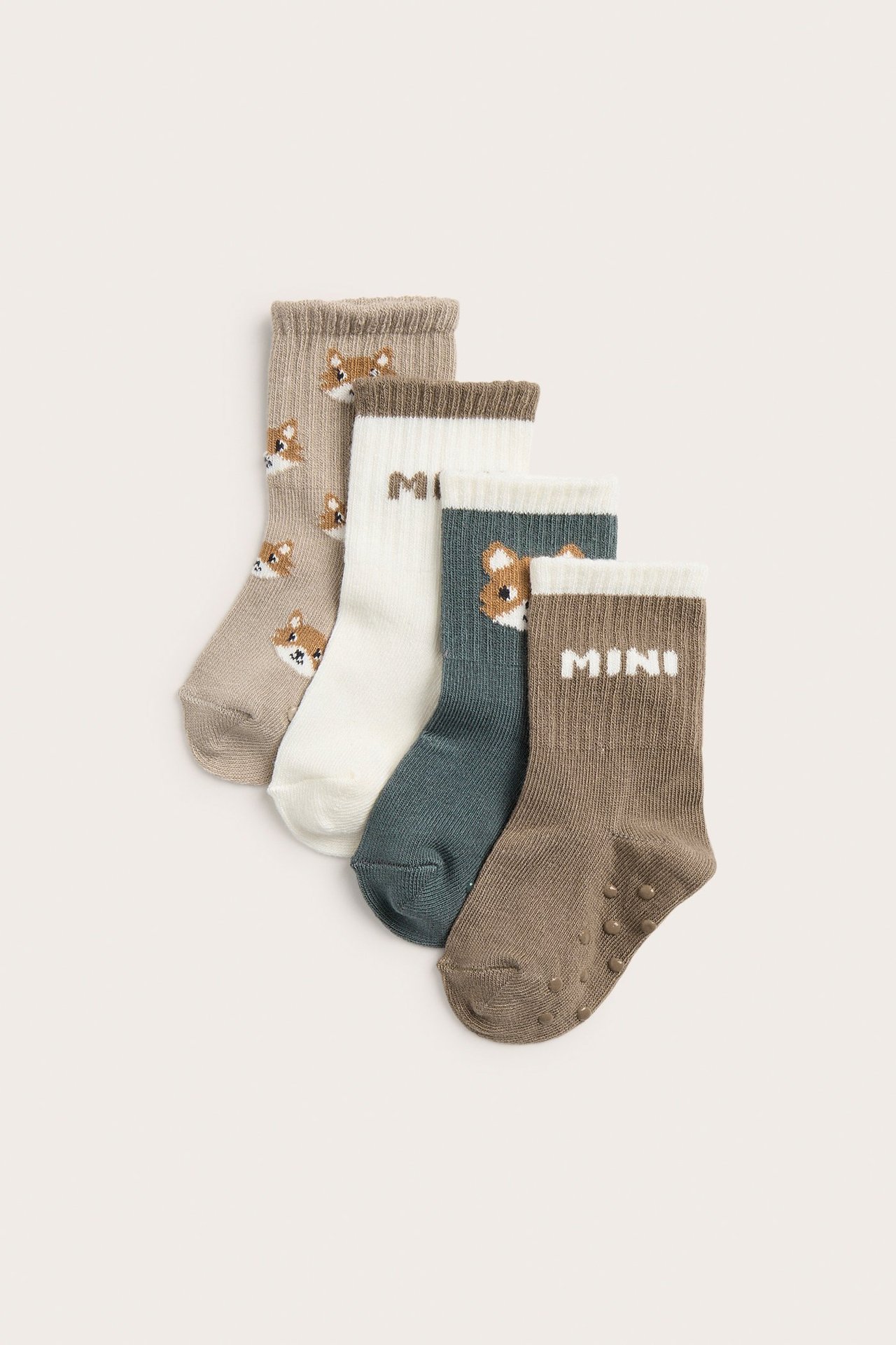 Edestä neljä vauvansukkaa: beige ketulla, luonnonvalkoinen, tumma turkoosi ketulla, ja khakinvärinen liukuesteillä.