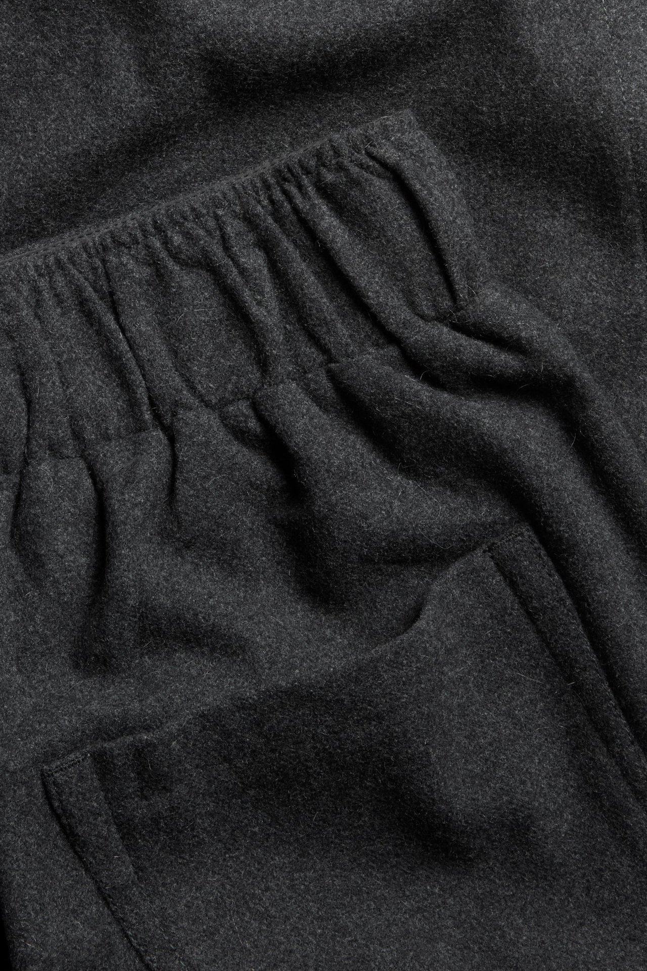 Zbliżenie na ciemnoszare spodnie z mieszanki wełny z elastyczną talią i boczną kieszenią.