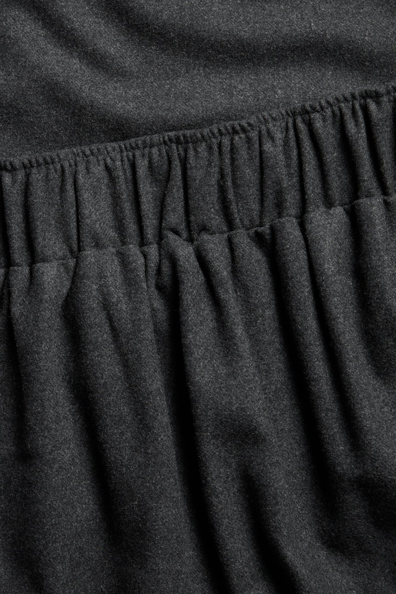 Zbliżenie ciemnoszarej, melanżowej spódnicy z mieszanki wełny z elastyczną talią.