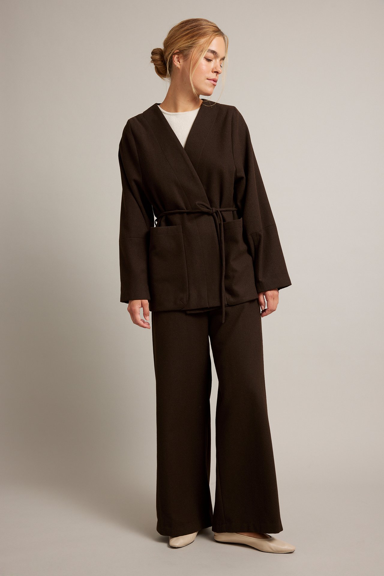 Kobieta w brązowym zestawie kimono, białym T-shircie i beżowych balerinach.