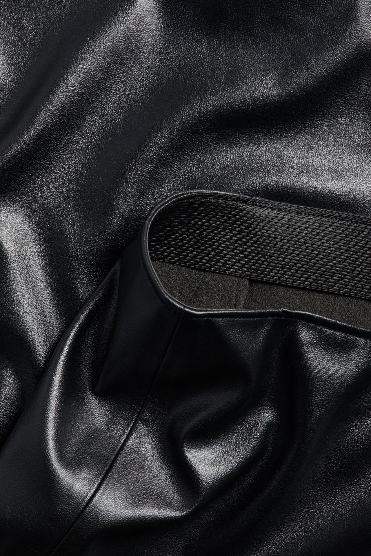 Zbliżenie czarnej spódnicy ołówkowej z PU z elastycznym pasem.