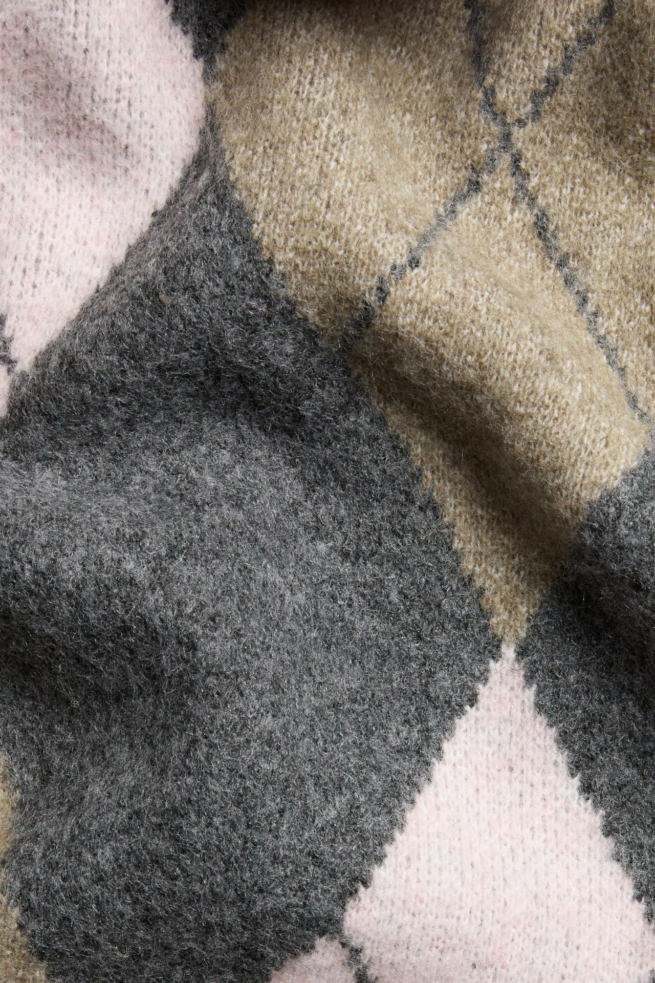 Zbliżenie na ciemnoszary, jasnobeżowy i jasnoróżowy sweter dzianinowy w romby.