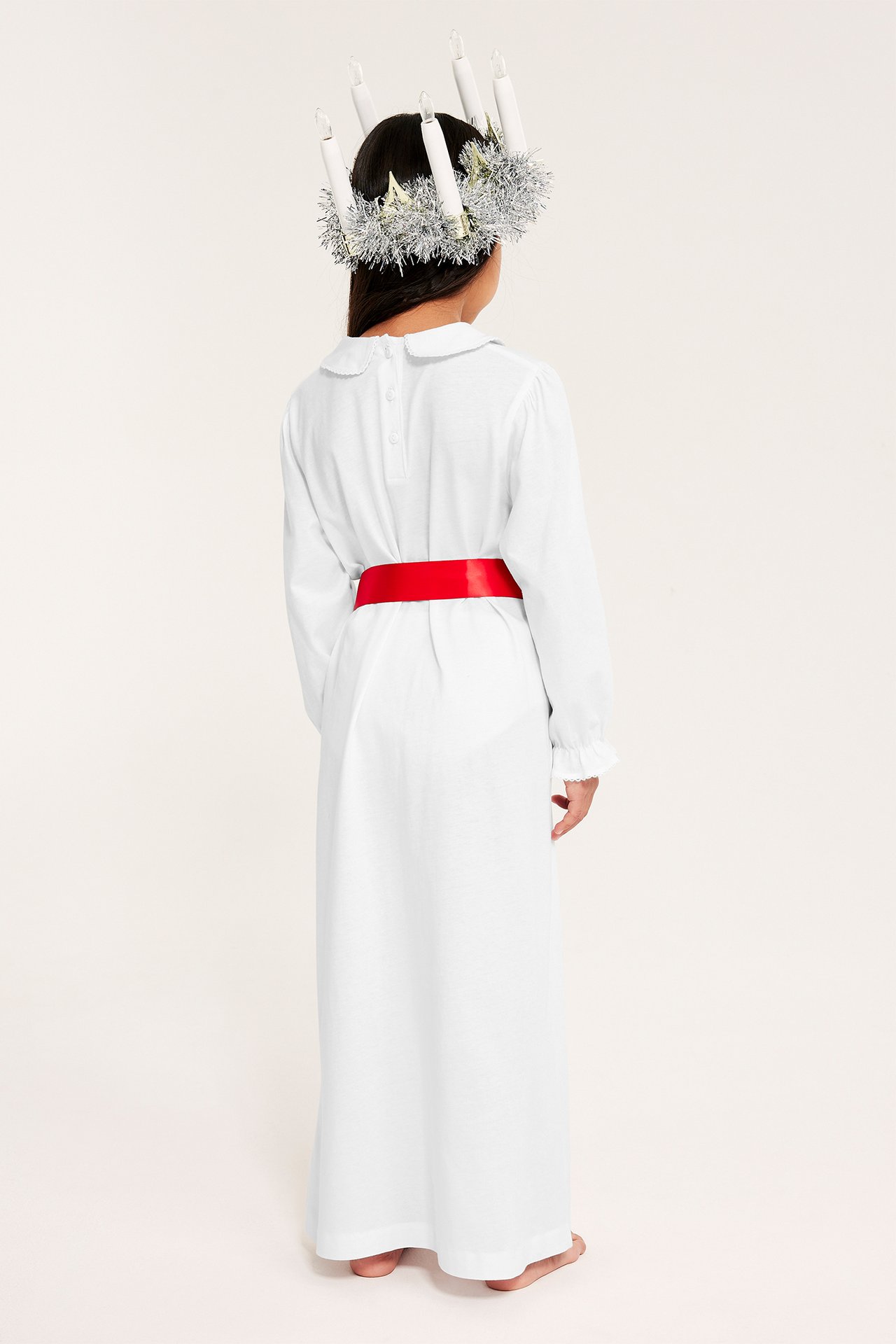 Jente i hvitt bomulls Lucia-nattlinne, lang, med elastikk ved ermene, bakfra.
