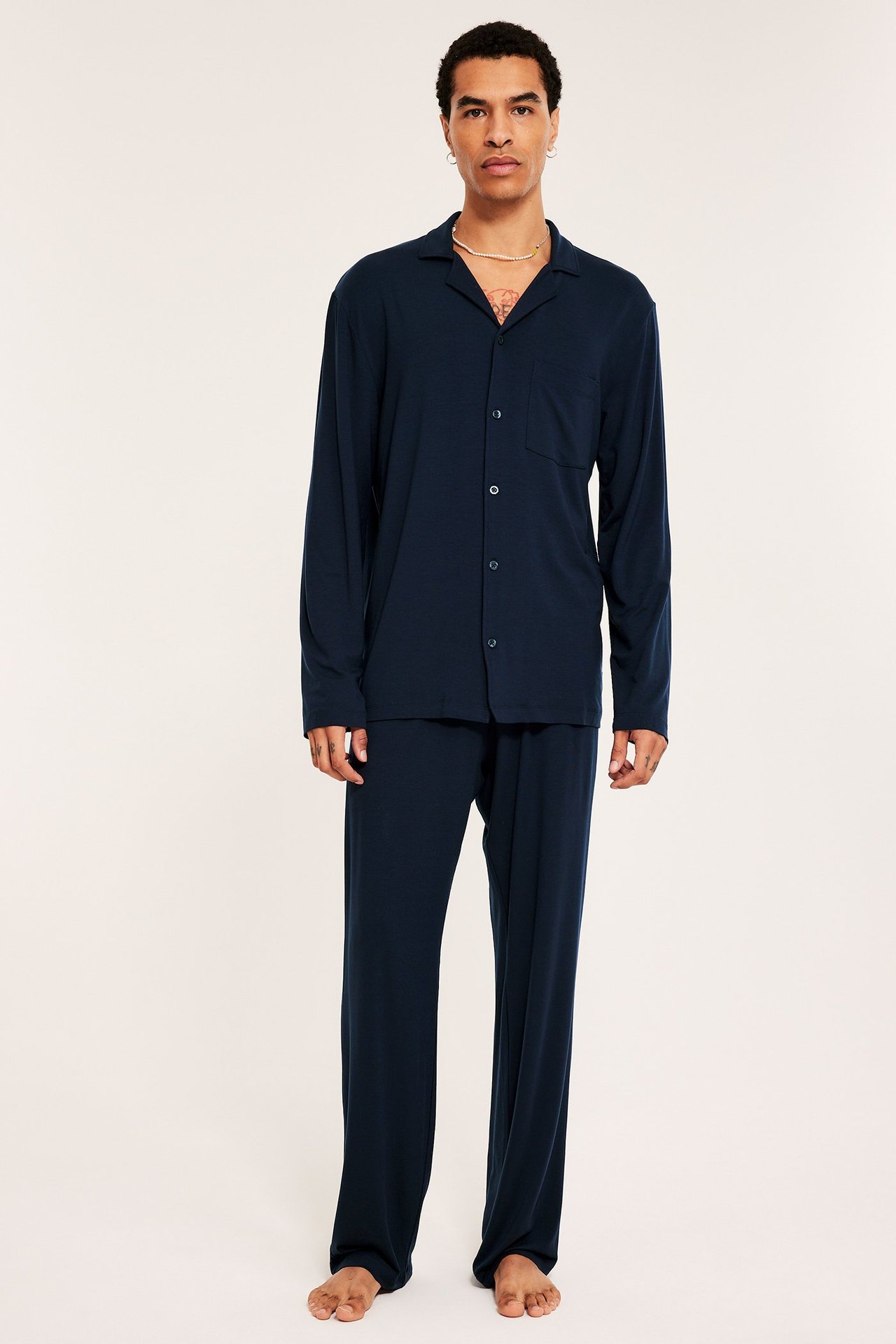 Mies tummansinissä Tencel-pyjamasasussa pitkähihainen paita ja löysät housut.