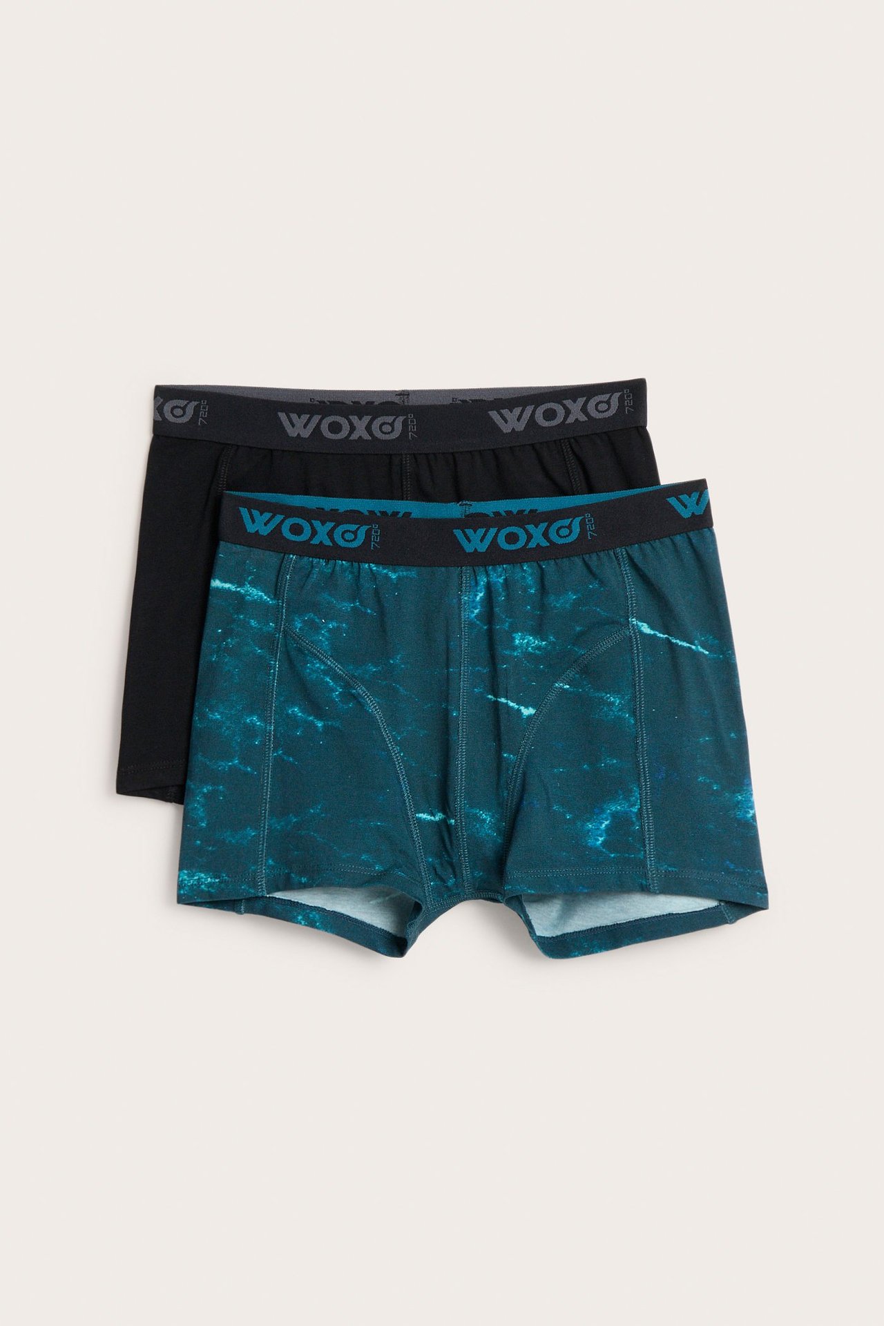 Widok z przodu dwóch par bokserek dziecięcych: jedne zielone we wzory, drugie czarne, z gumką w pasie.