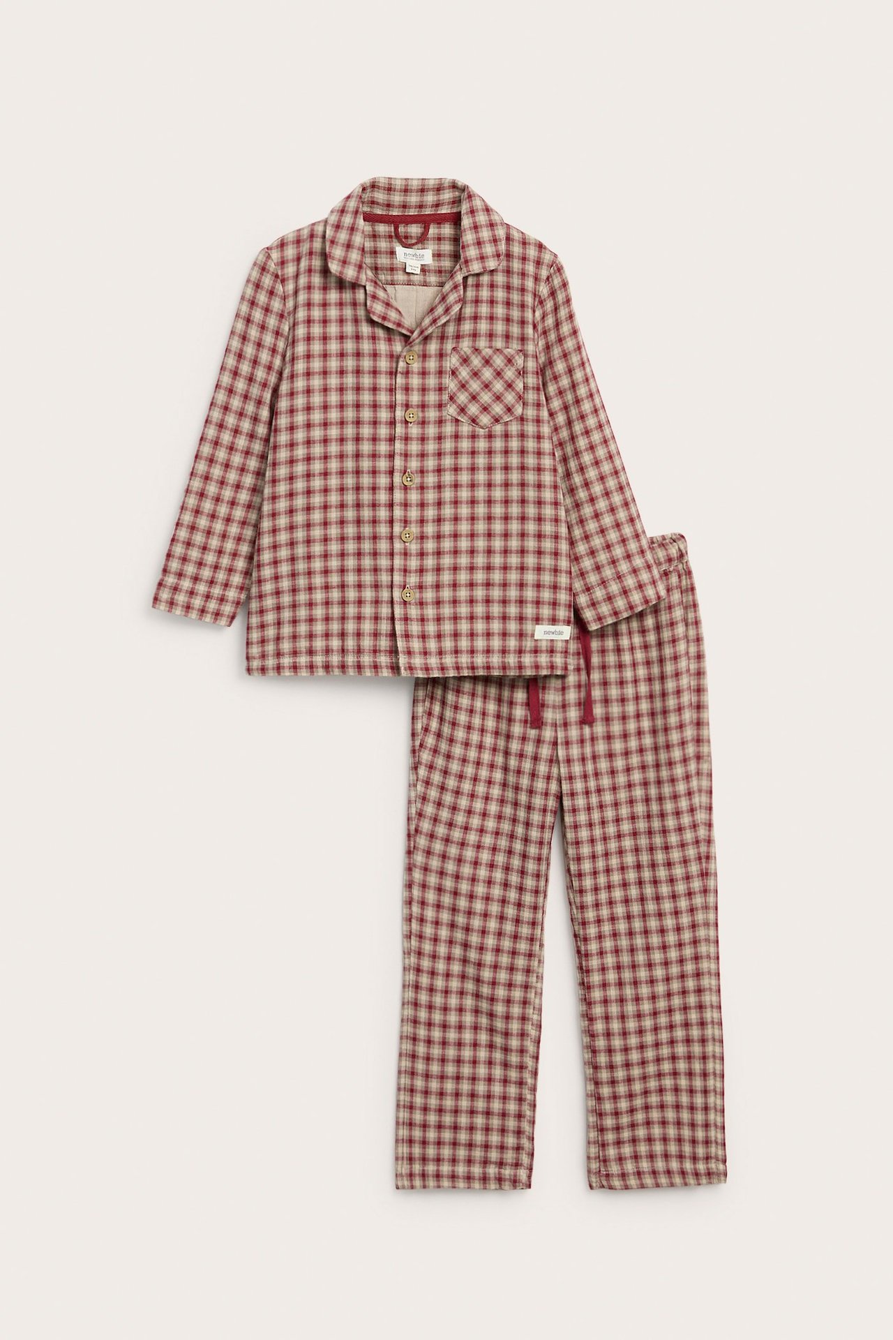 Frontvy av en barnpyjamas i rött och beige rutigt bomull: kragad skjorta och byxor med dragsko.