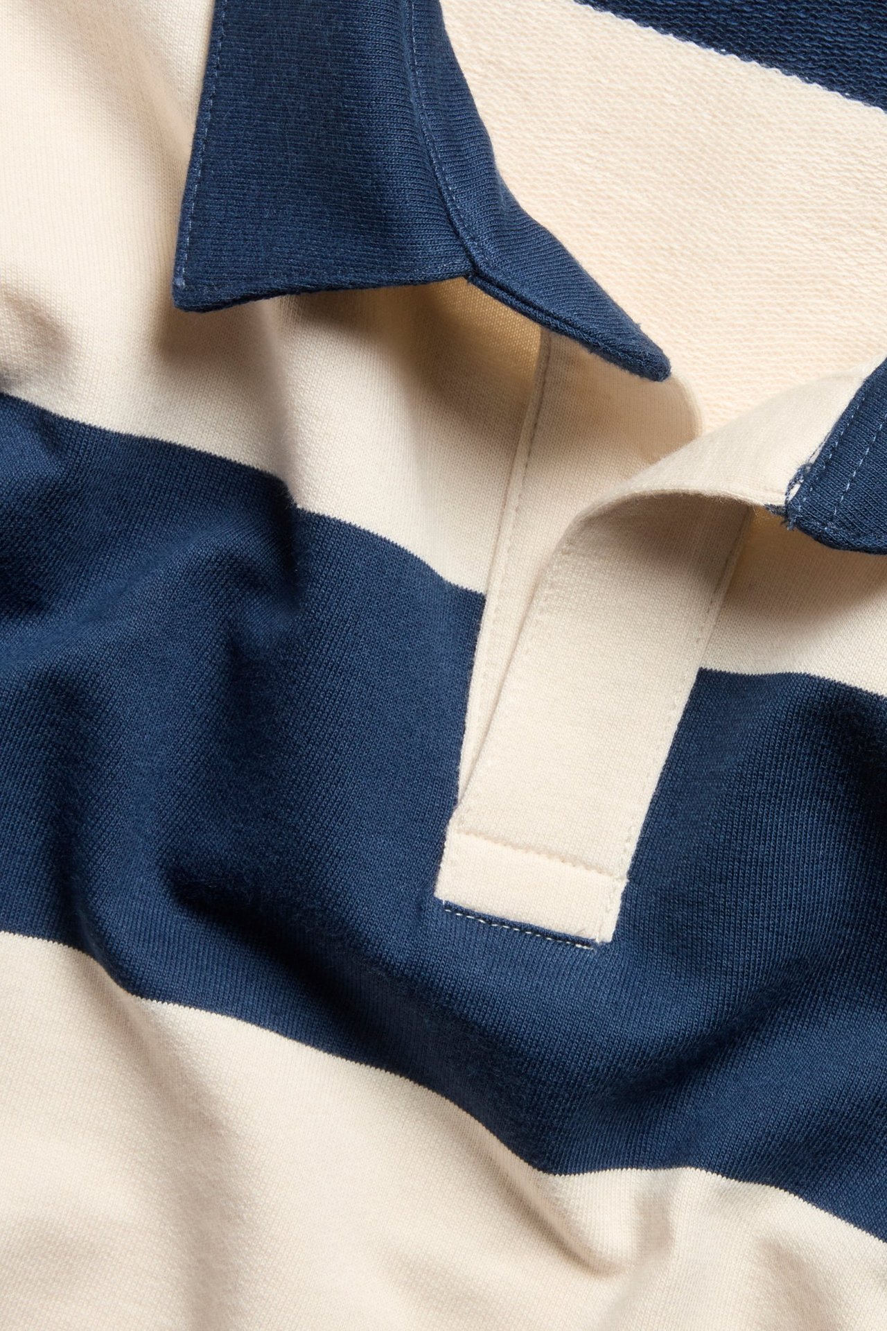 Zbliżenie: bawełniana bluza polo w paski, jasnobeżowe i ciemnoniebieskie, z kołnierzykiem.