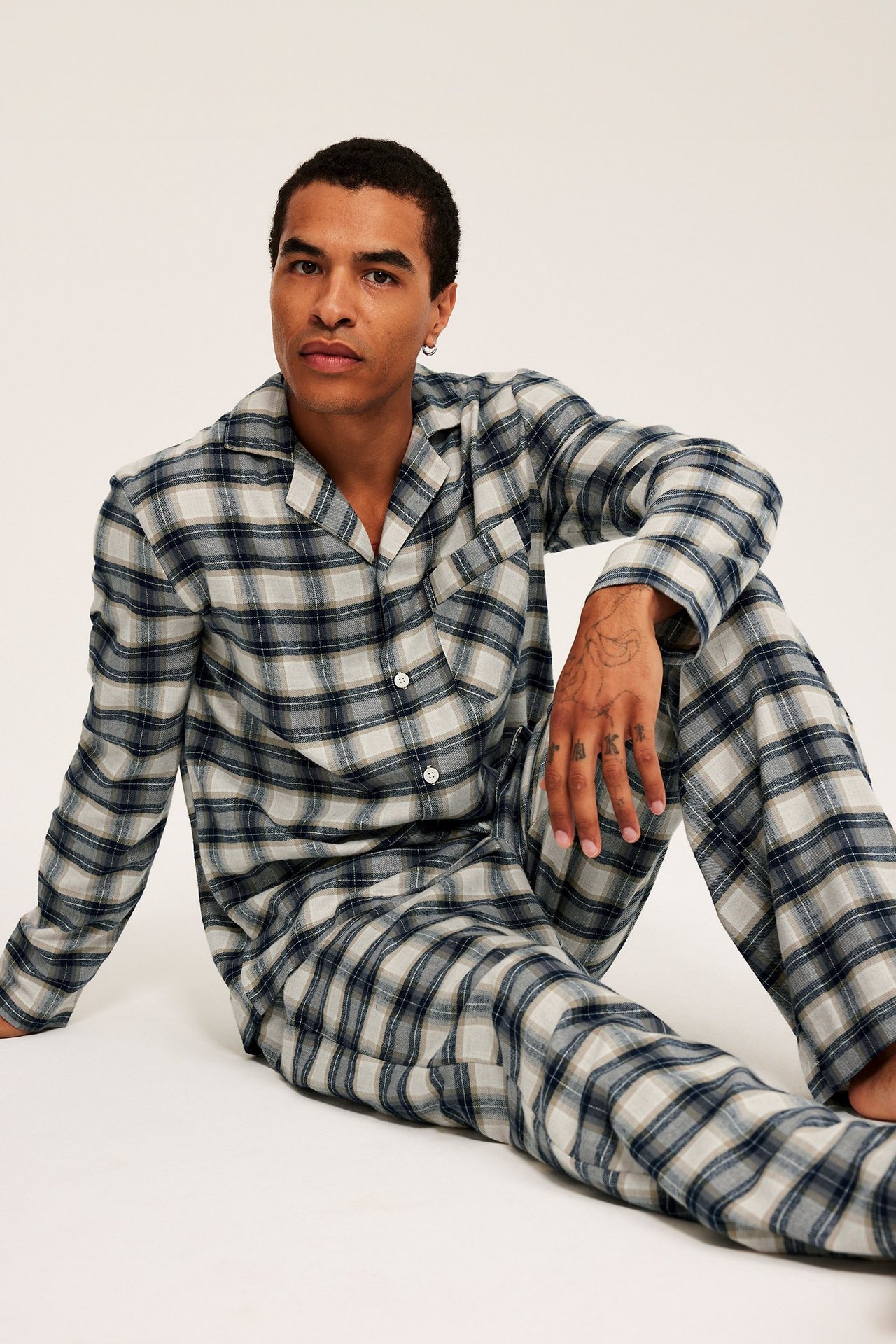 Widok z przodu: mężczyzna w niebiesko-beżowej piżamie flanelowej w kratę, zapinana góra i spodnie z gumką.