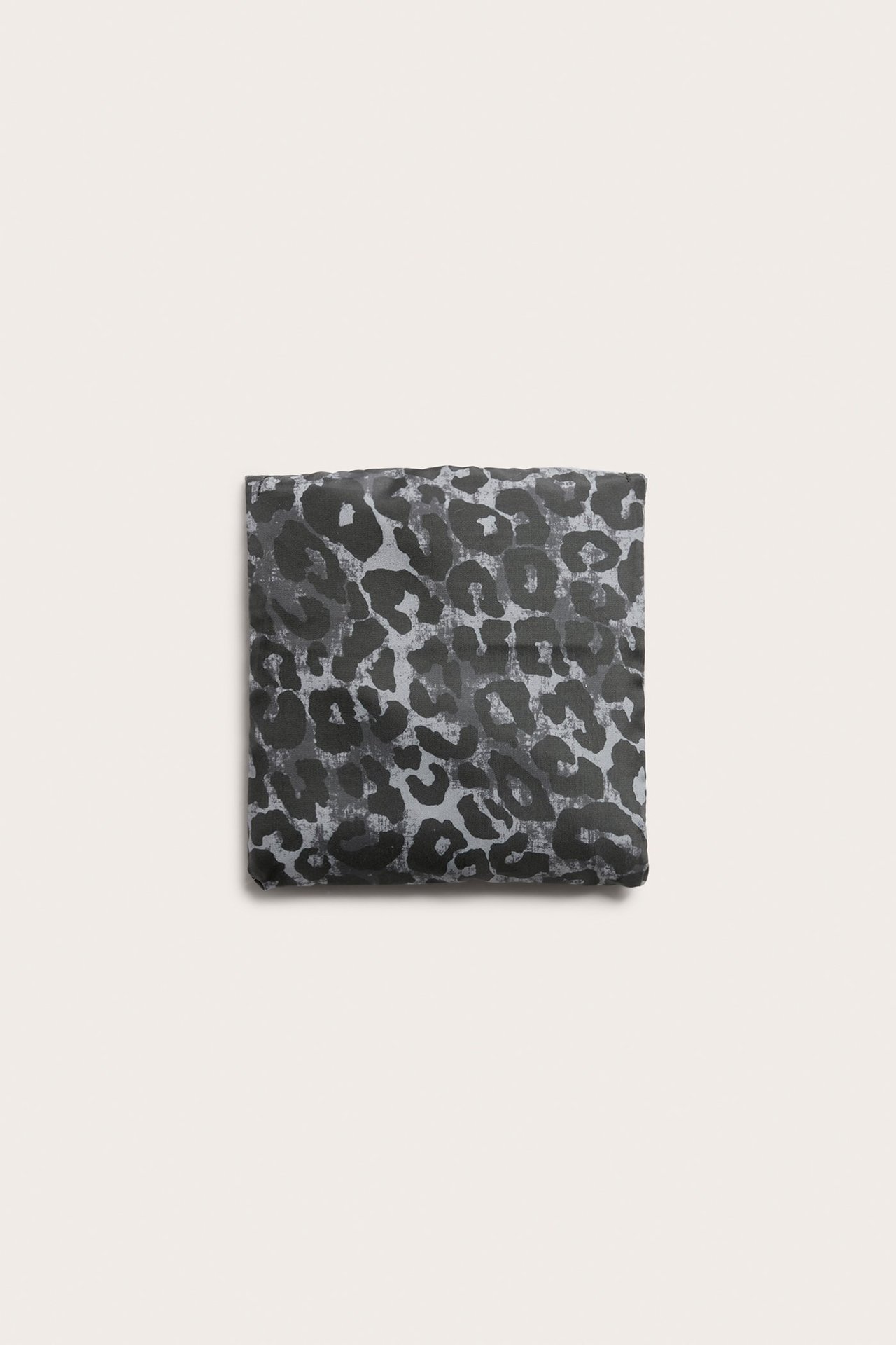 Ylhäältä kuvattu taitettu harmaa polyesterinen ostoskassi leopardikuviolla.