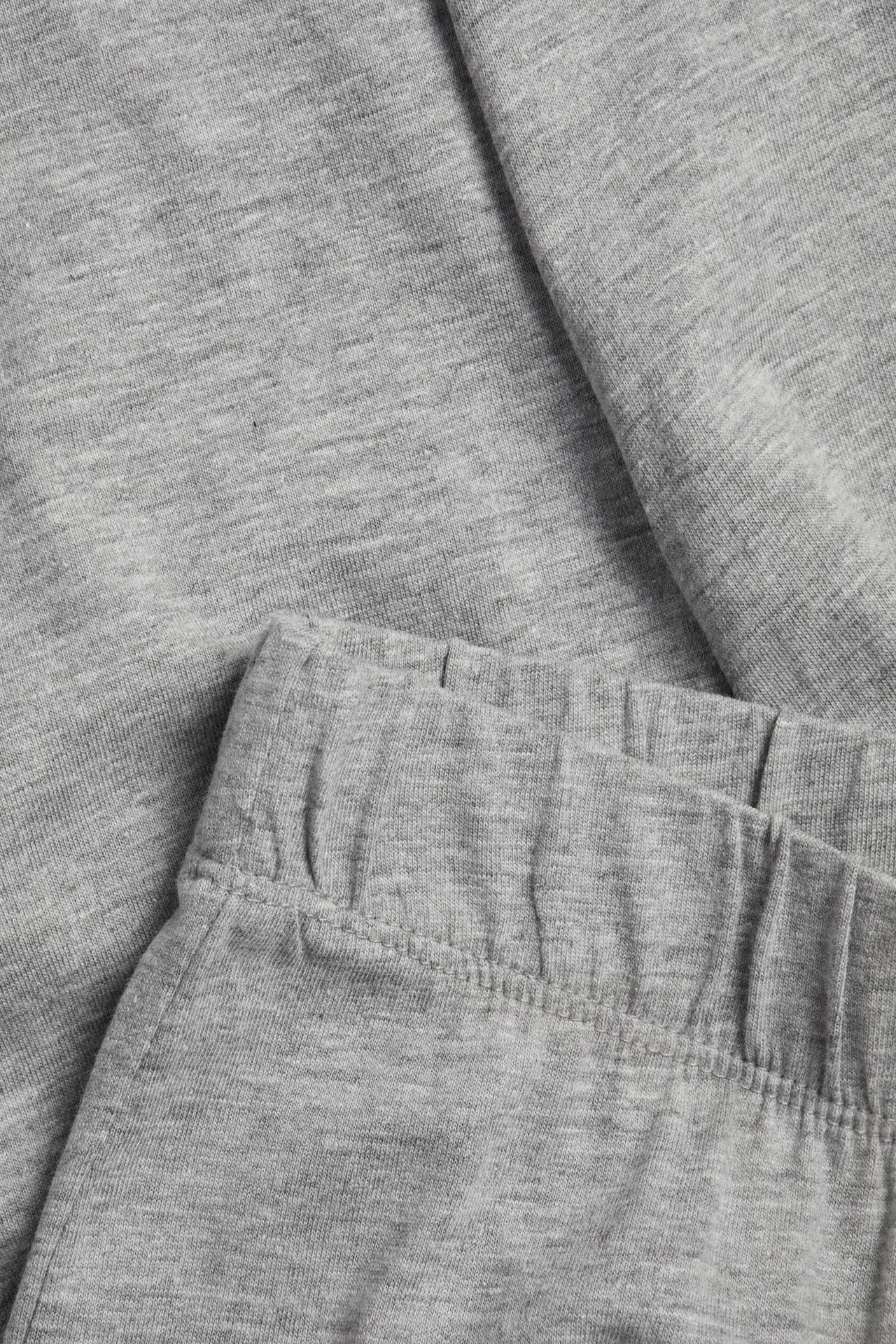 Zbliżenie jasnoszarych melanżowych spodni piżamowych z dżerseju z elastycznym pasem.