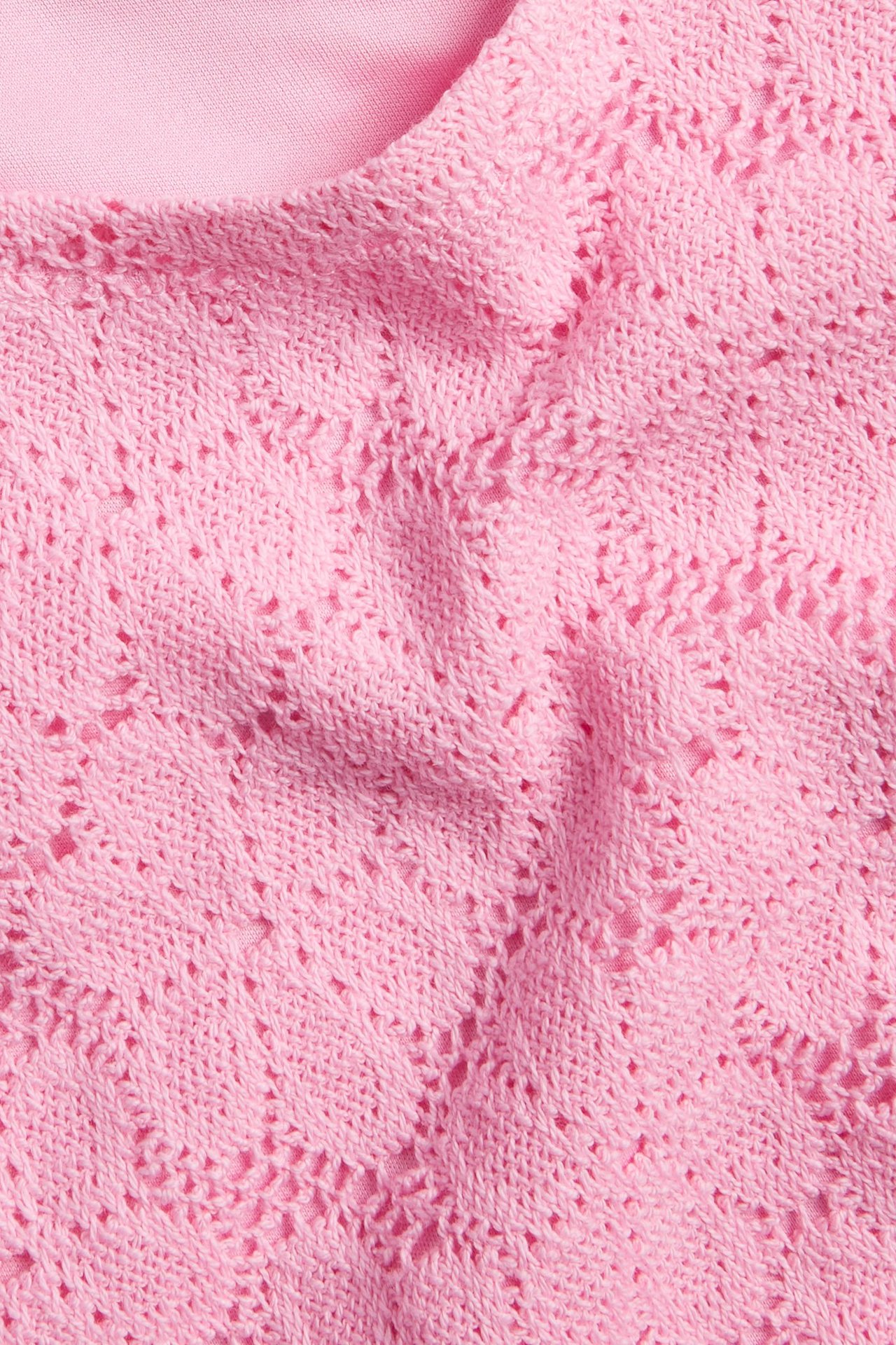 Zbliżenie różowego koronkowego topu z podszewką poliestrową.