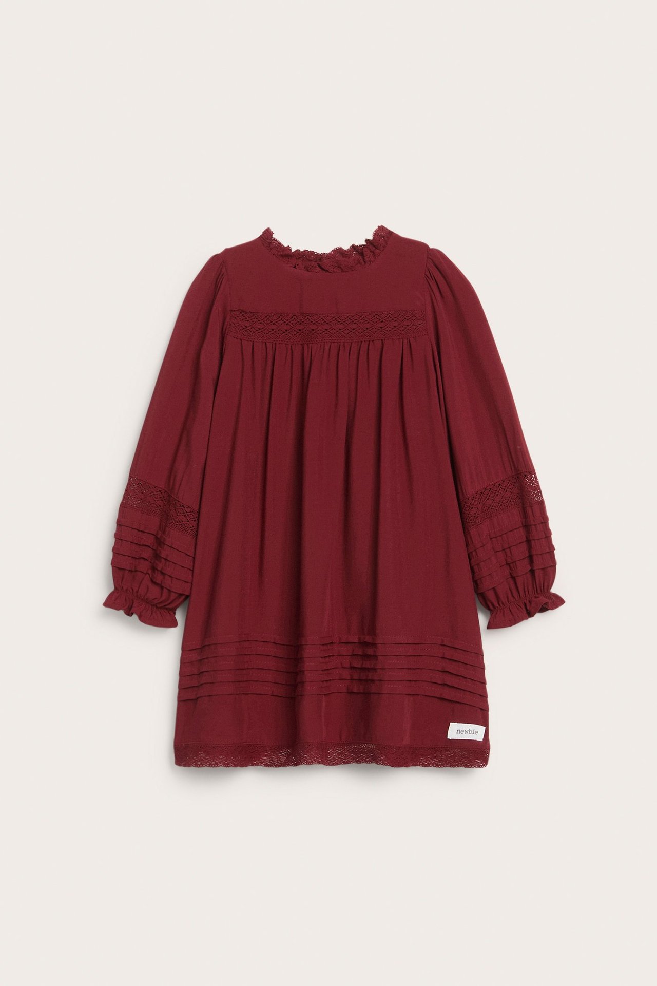 Widok z przodu, czerwona wiskozowa sukienka dziecięca z koronkami, zakładkami i falbankami przy rękawach.