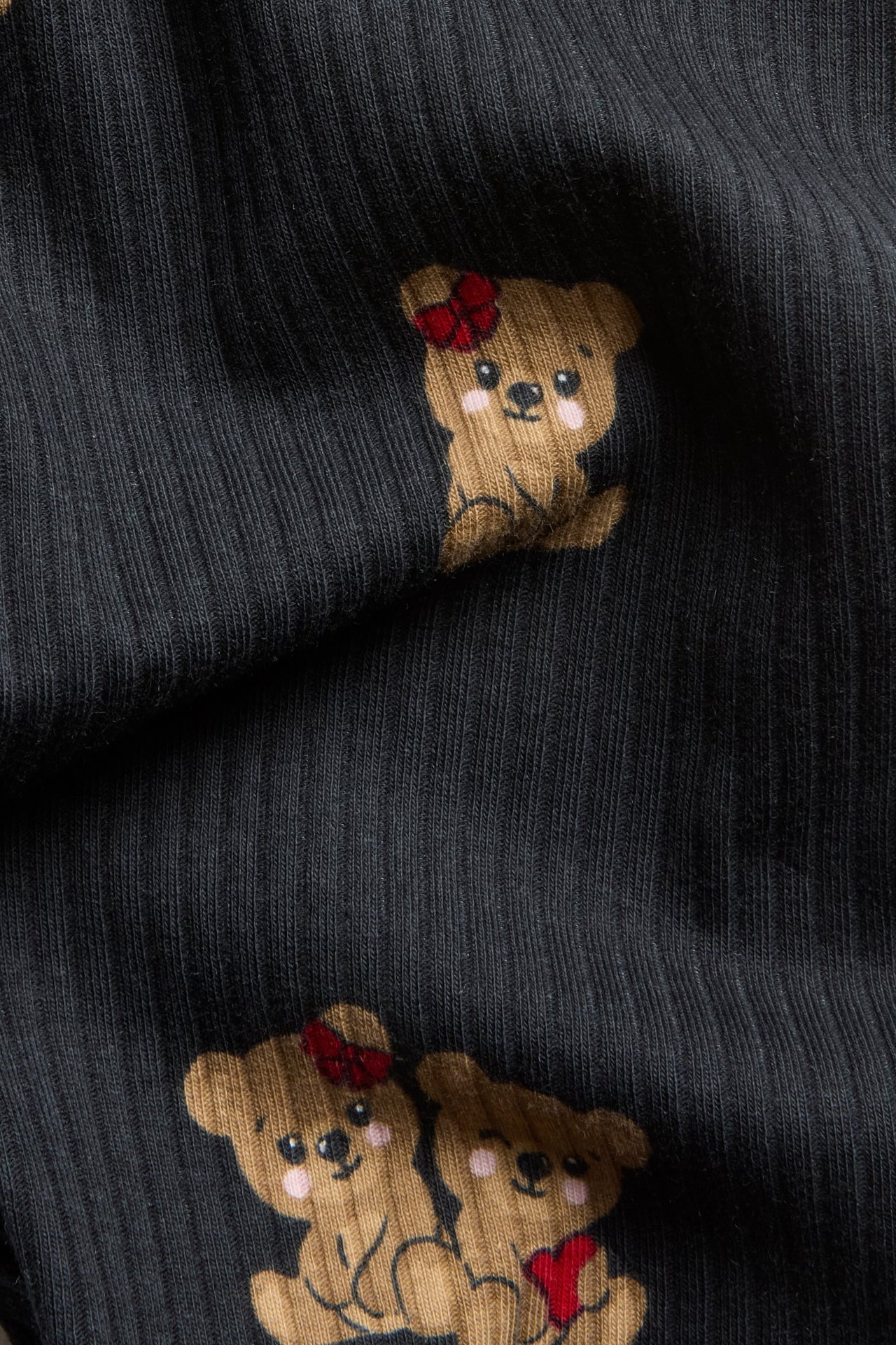 Zbliżenie na czarne prążkowane legginsy z wzorem w brązowe misie.