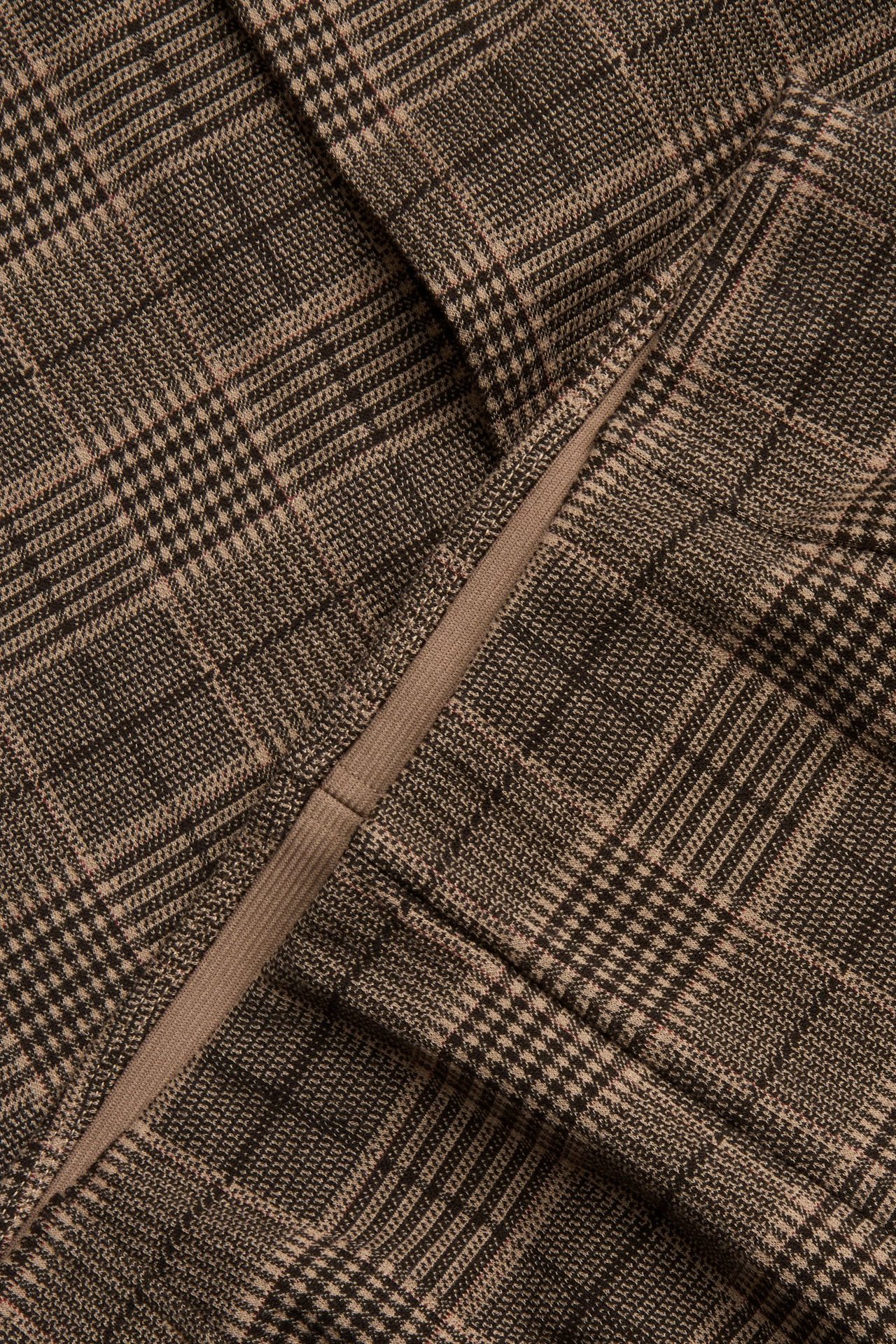 Zbliżenie na jasnobrązowy, kraciasty materiał spodni pull-on z prążkowanym detalem.