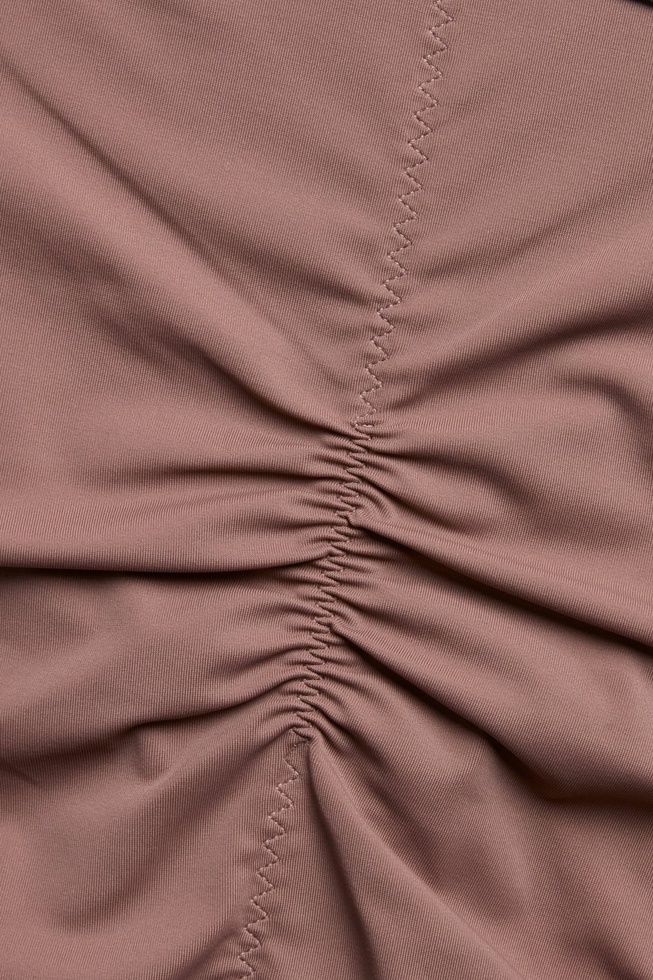 Zbliżenie na ciemnoróżowe modelujące figi hipster z marszczeniem na środku i zygzakowatymi szwami.