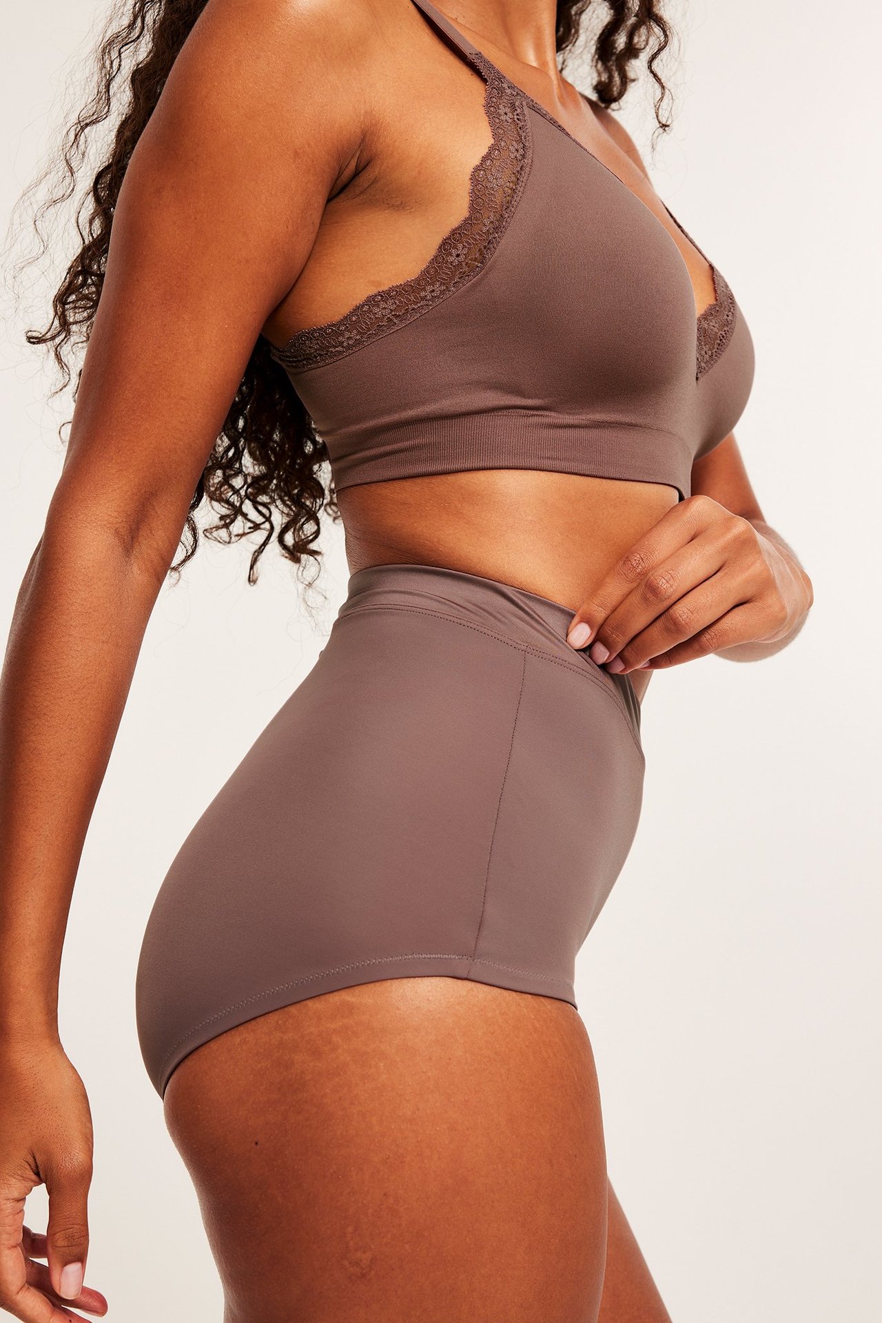 Sidebilde av kvinne i mørk rosa høy midje shaping hipster truse og matchende blondebralette.