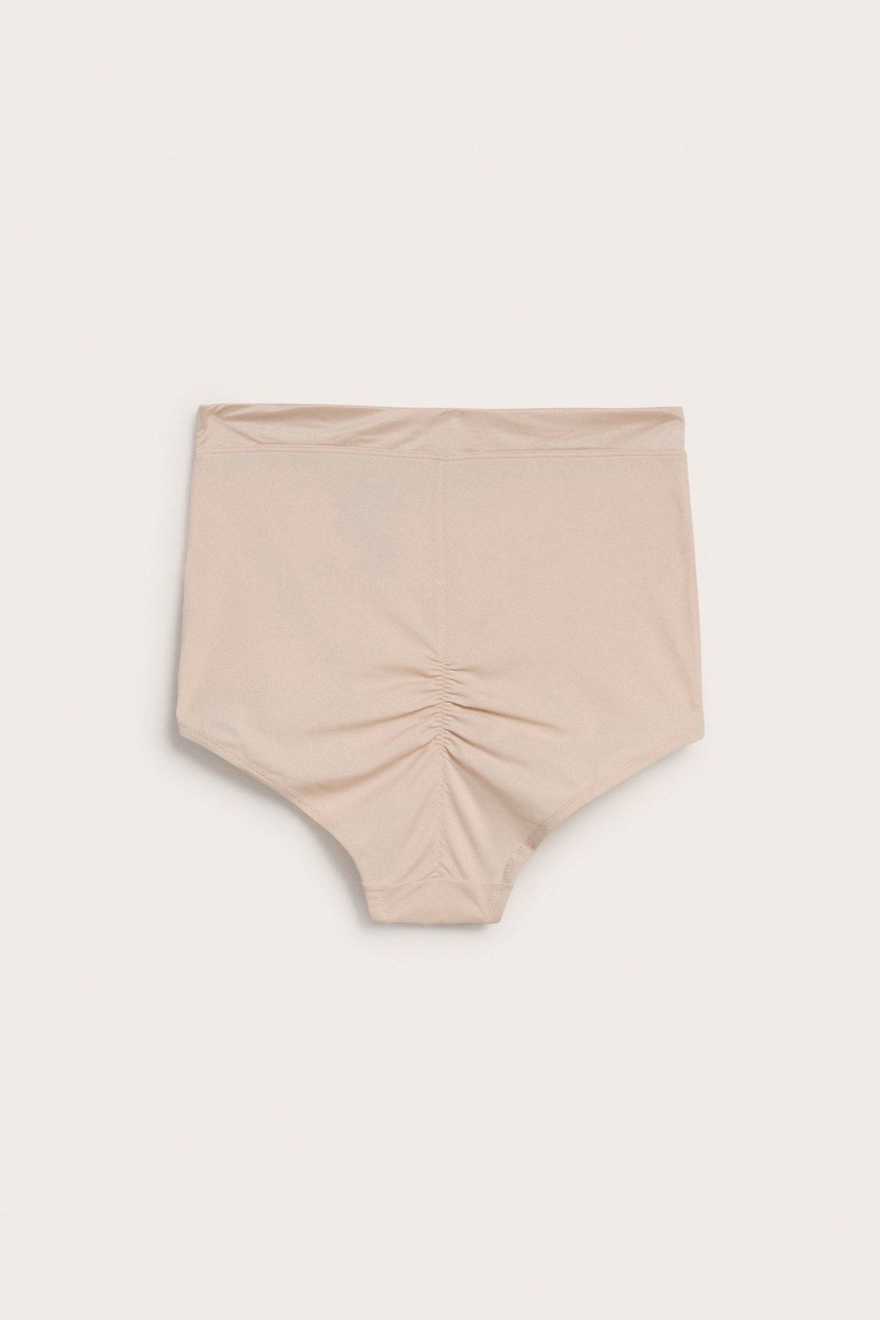 Framifrån, ljusbeige hög midja shaping hipstertrosa med rynkning mitt bak.