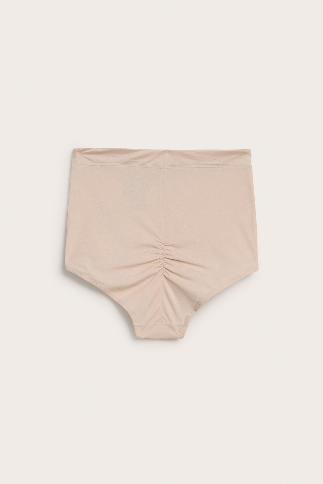 Framifrån, ljusbeige hög midja shaping hipstertrosa med rynkning mitt bak.