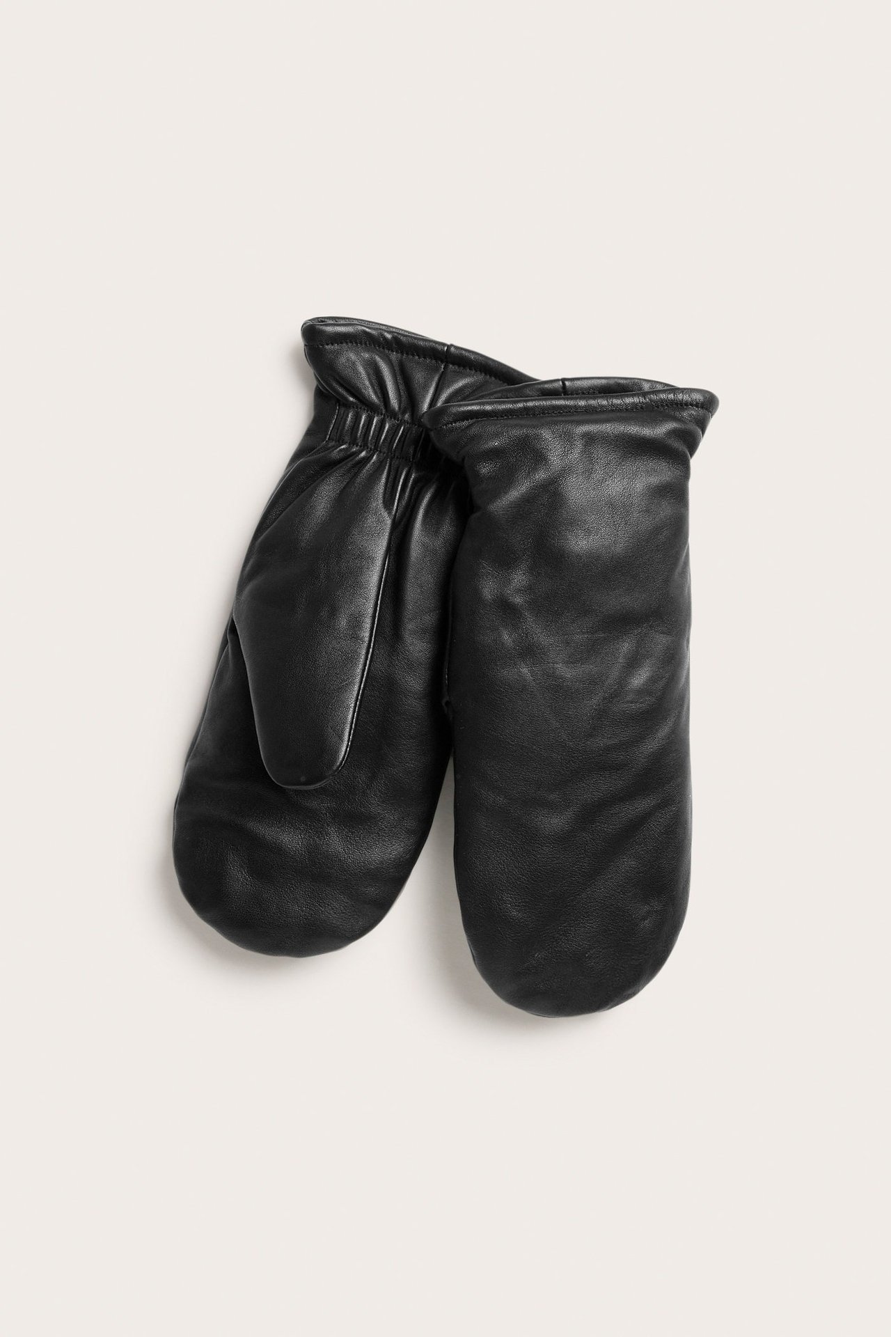 Widok z przodu pary czarnych skórzanych rękawiczek z marszczonymi mankietami, leżących płasko.