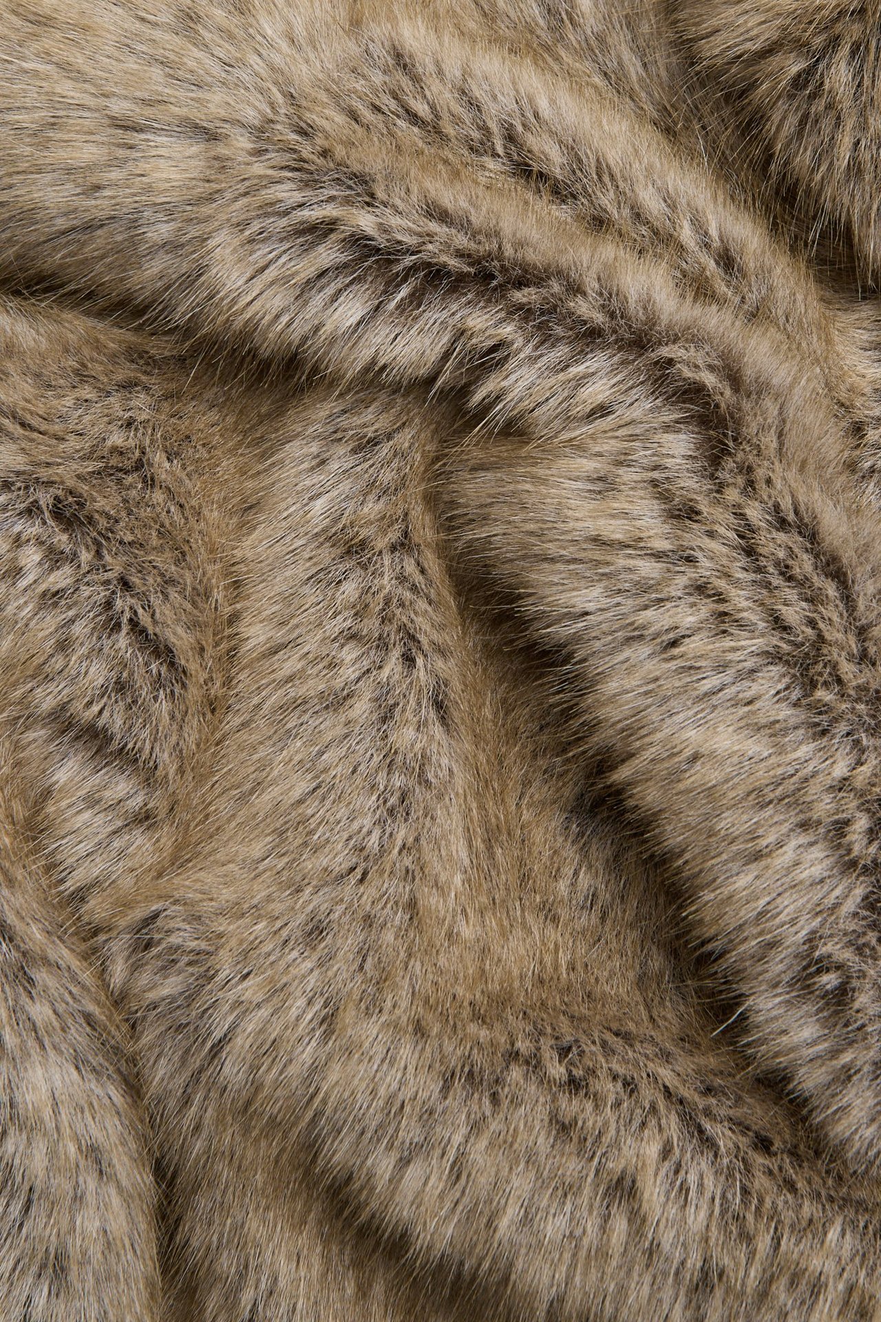 Nærbilde av beige fuskepelsjakke stoff med varierende brune og beige toner.