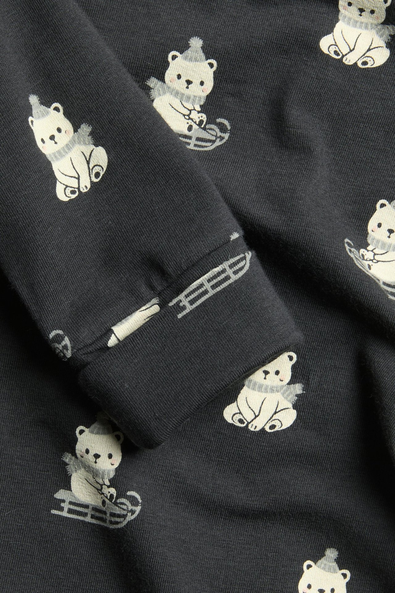 Zbliżenie na ciemnoszare body dla niemowląt z białymi niedźwiedziami polarnymi w czapkach na sankach.