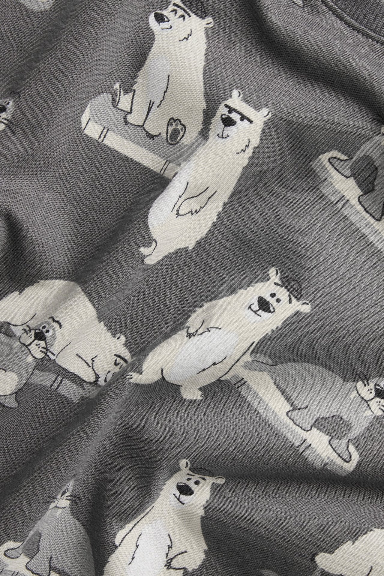 Zbliżenie szarej bawełnianej bluzy z nadrukiem białych niedźwiedzi polarnych i szarych morsów.