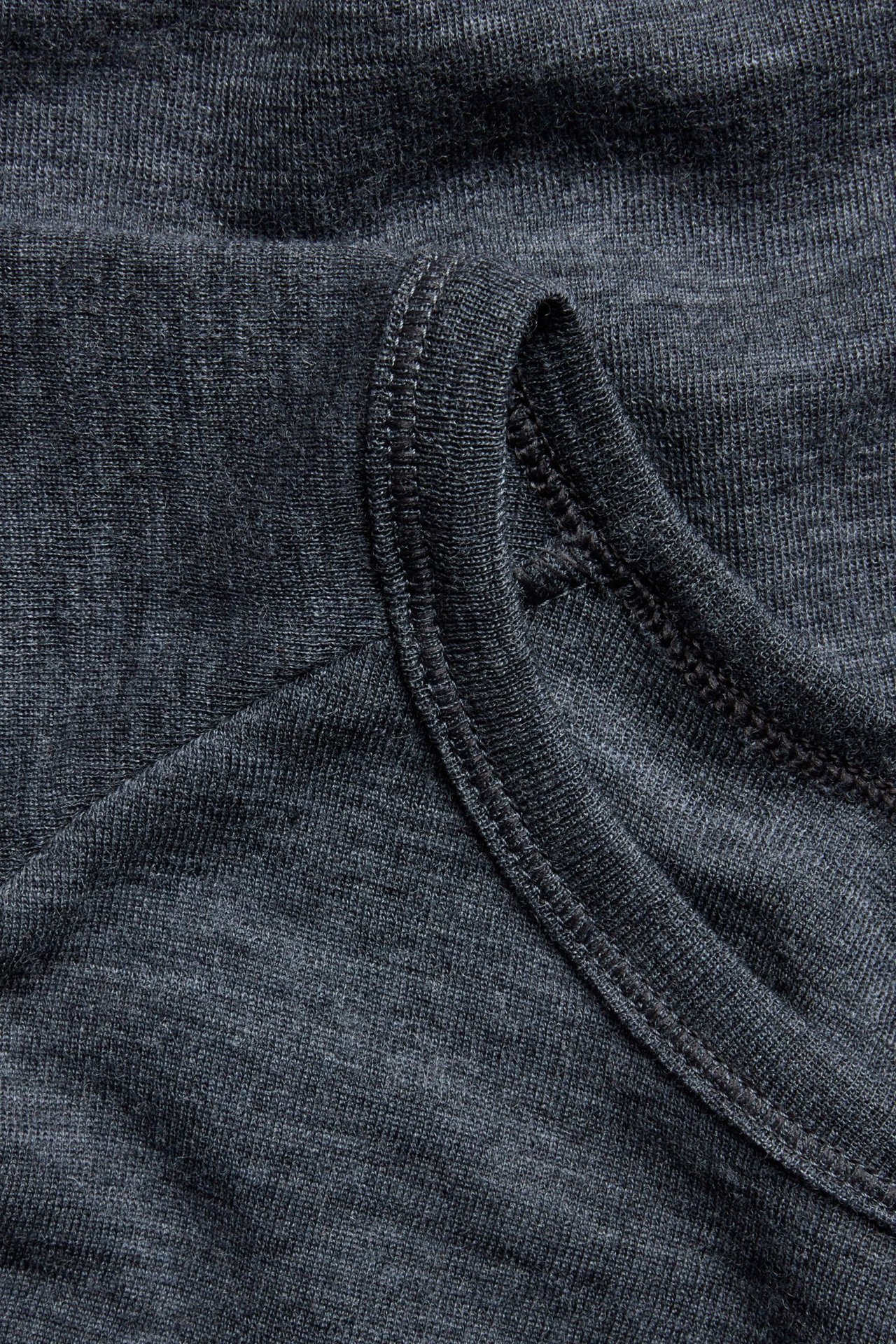 Zbliżenie czarnej melanżowej koszulki termoaktywnej z wełny merynosów, ukazujące fakturę i szwy.