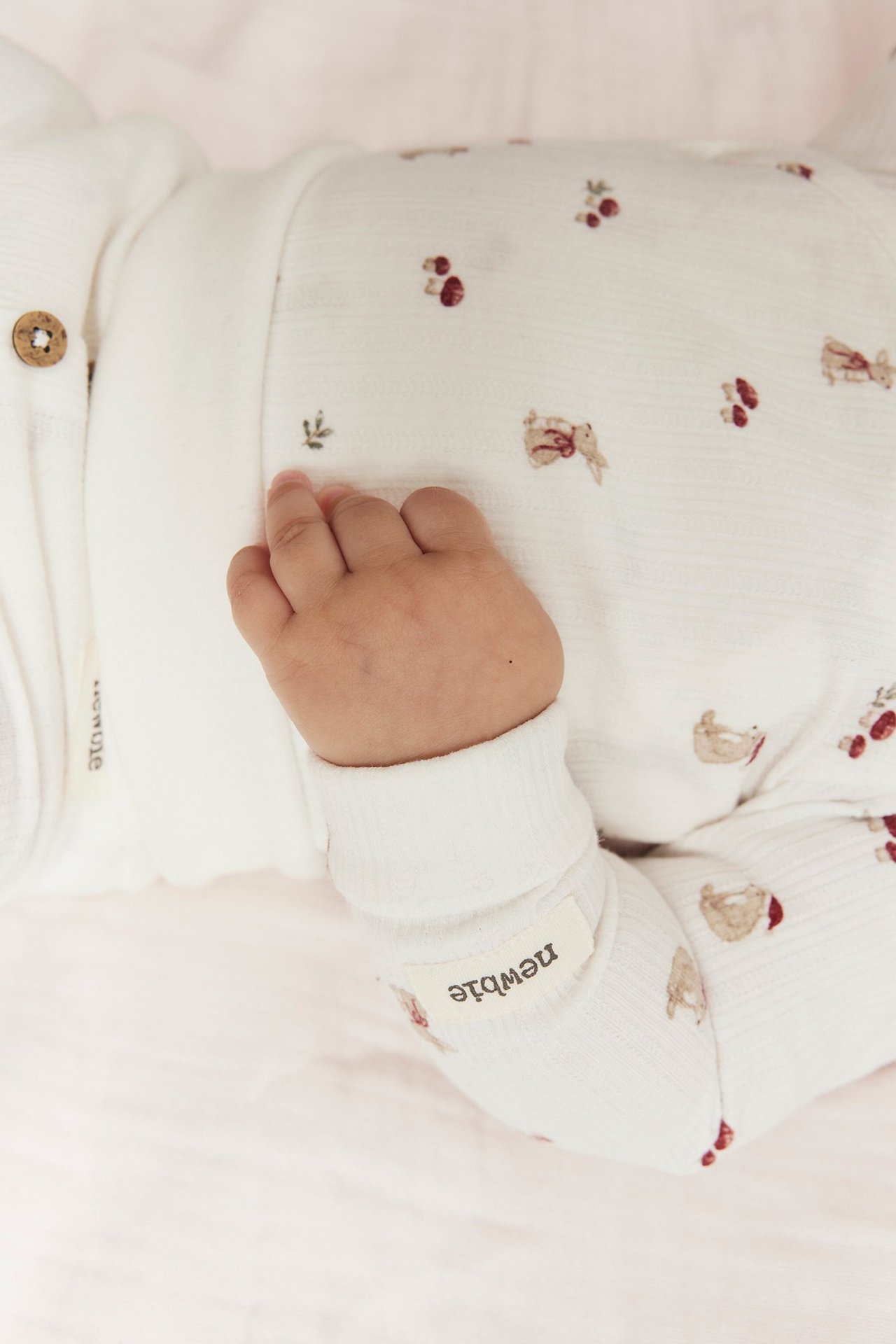 Lähikuva vauvasta, jolla on luonnonvalkoinen, pitkähihainen eläinkuvioinen kietaisubody.