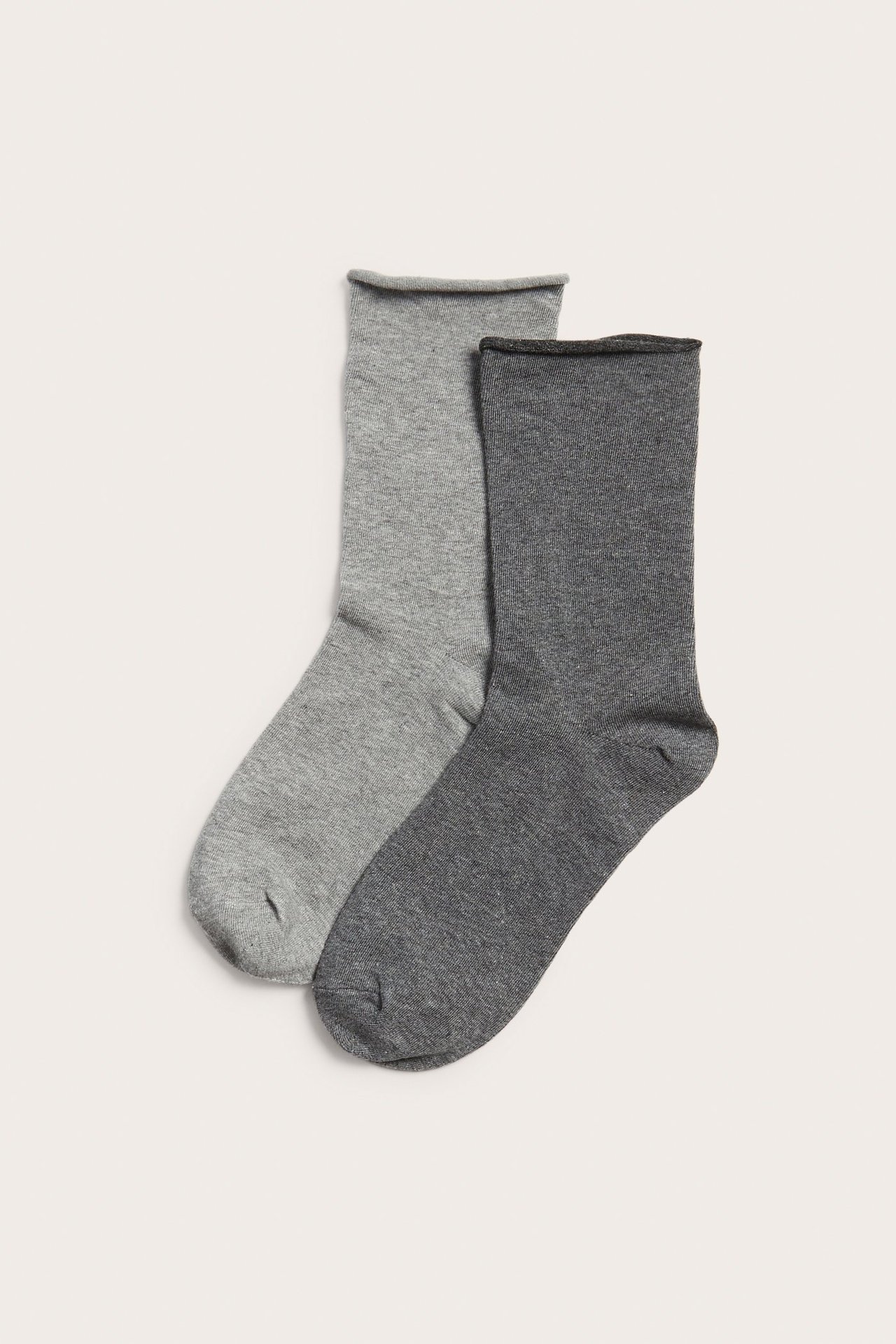 Ylhäältä kuvattu kahden melange-puuvillasukan pari: vaaleanharmaa ja tummanharmaa, rullatuilla reunoilla.