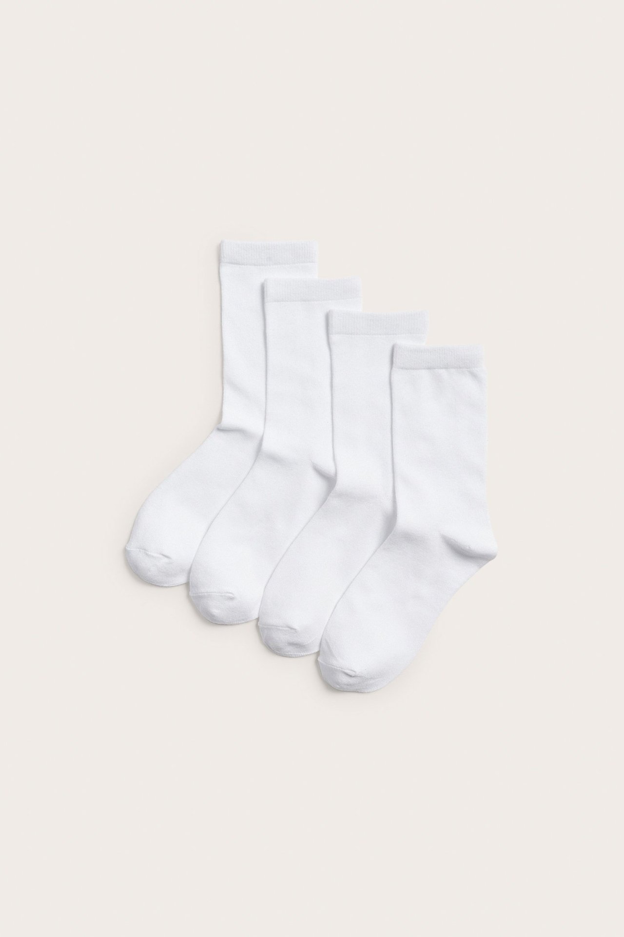 Widok z góry na cztery pary gładkich białych skarpetek z mieszanki bawełny.