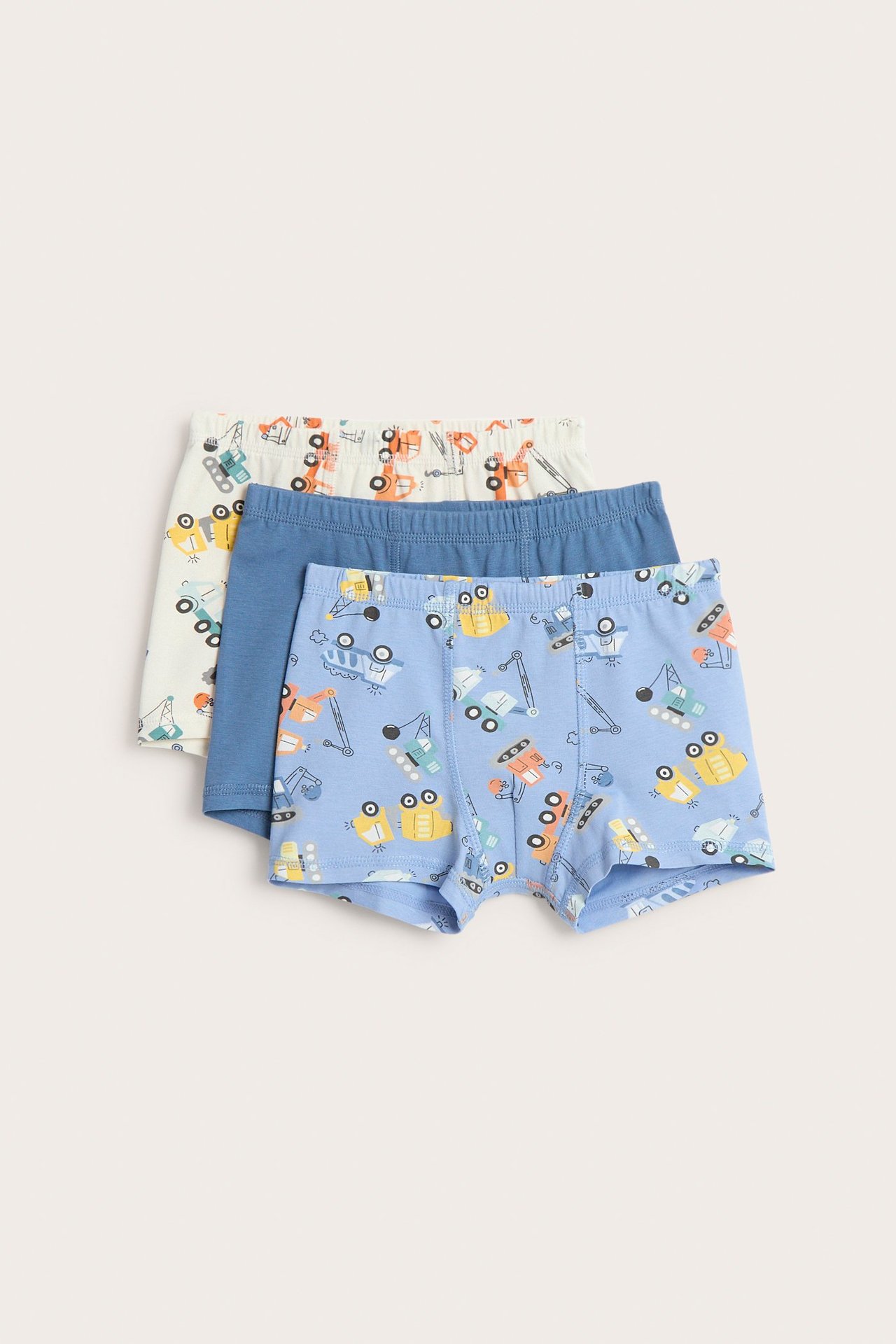 Frontvy av tre barnboxerkalsonger: ljusblå med fordonstryck, enfärgad blå och benvit med fordonstryck.