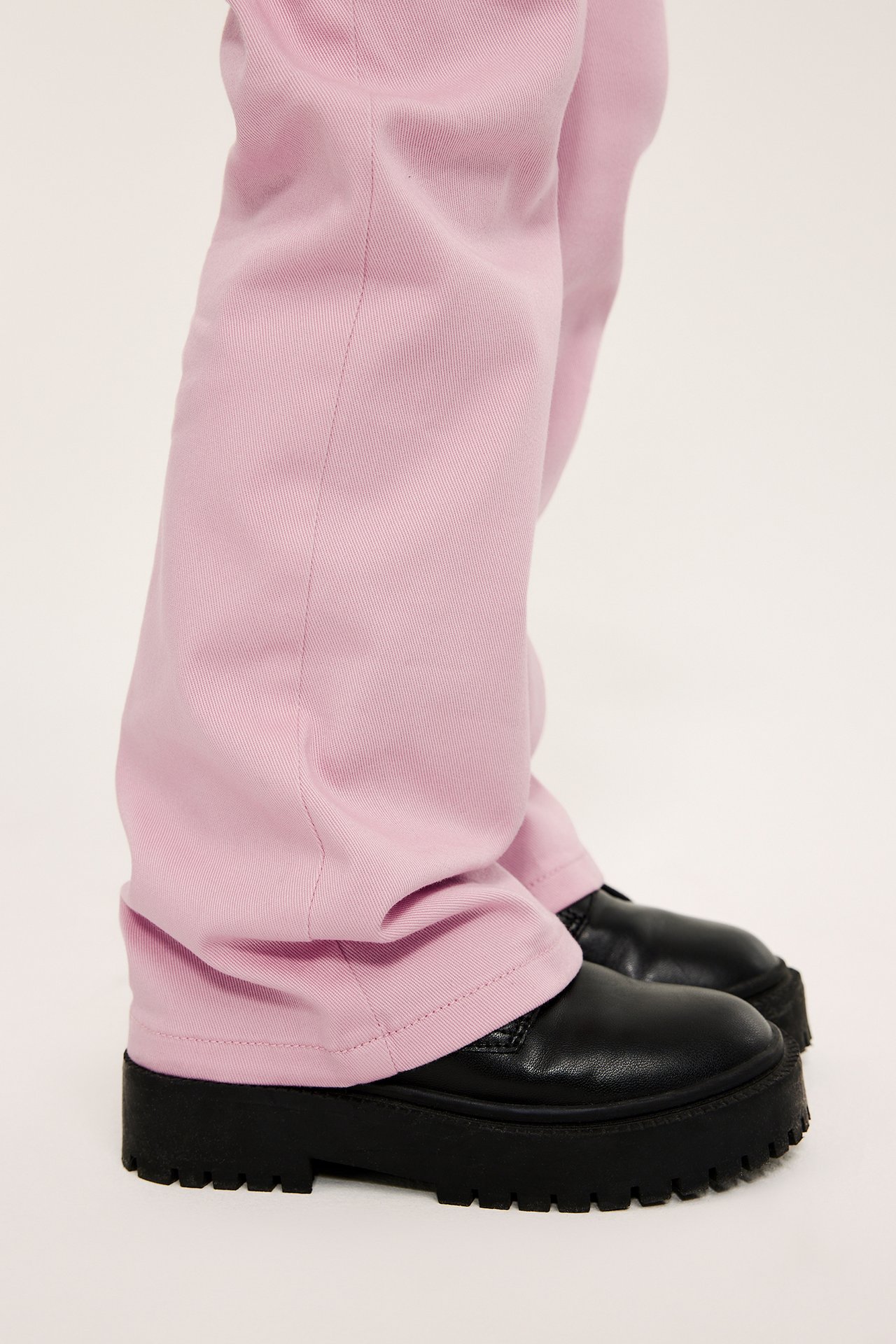 Närbild på ett barn som bär ljusrosa bootcut-jeans och svarta kängor med tjock sula.