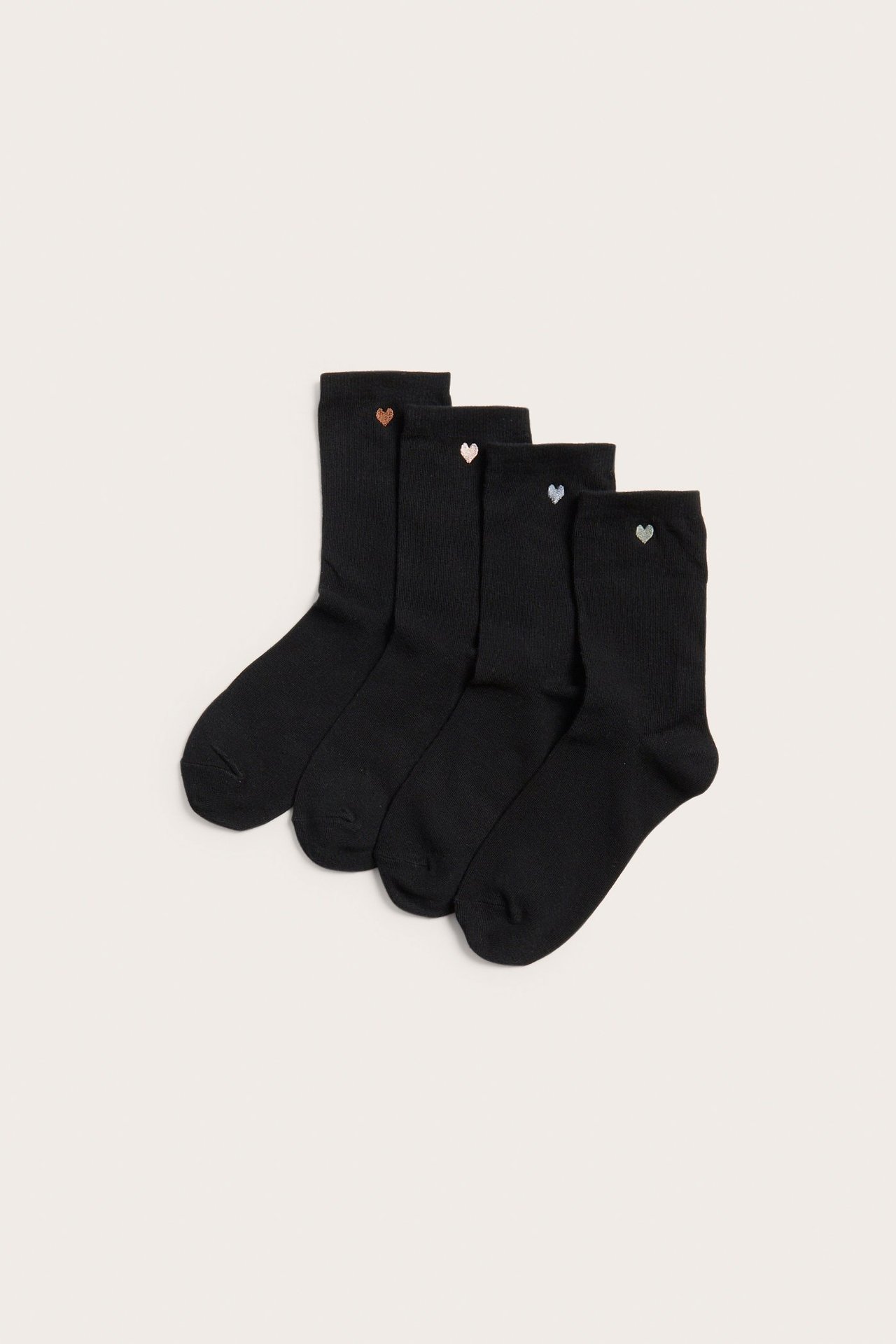 Ovenfra sett, fire svarte sokker, hver med et lite brodert hjerte i forskjellige metallfarger.