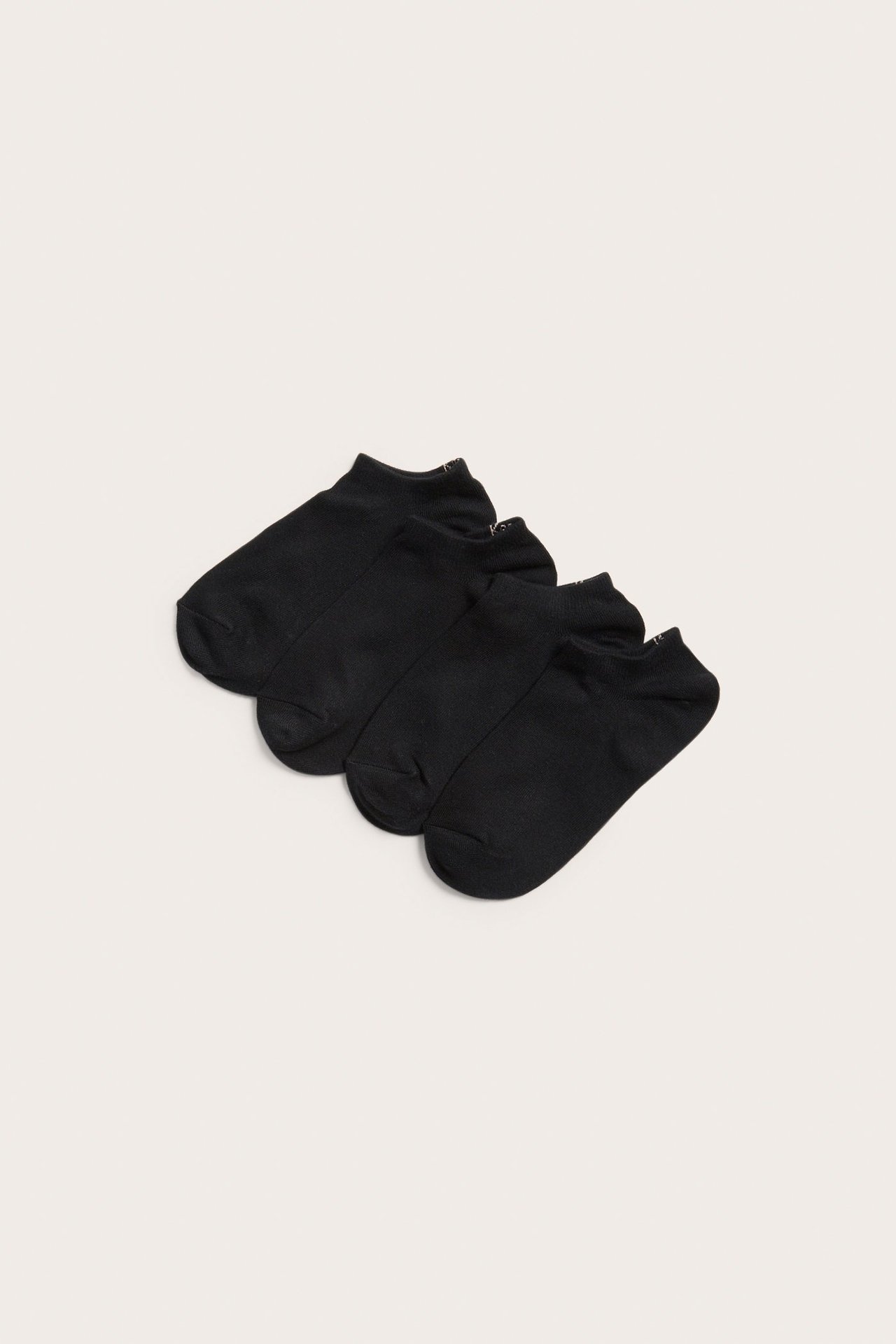 Widok z góry na cztery pary czarnych bawełnianych skarpetek typu stopki, starannie ułożonych.