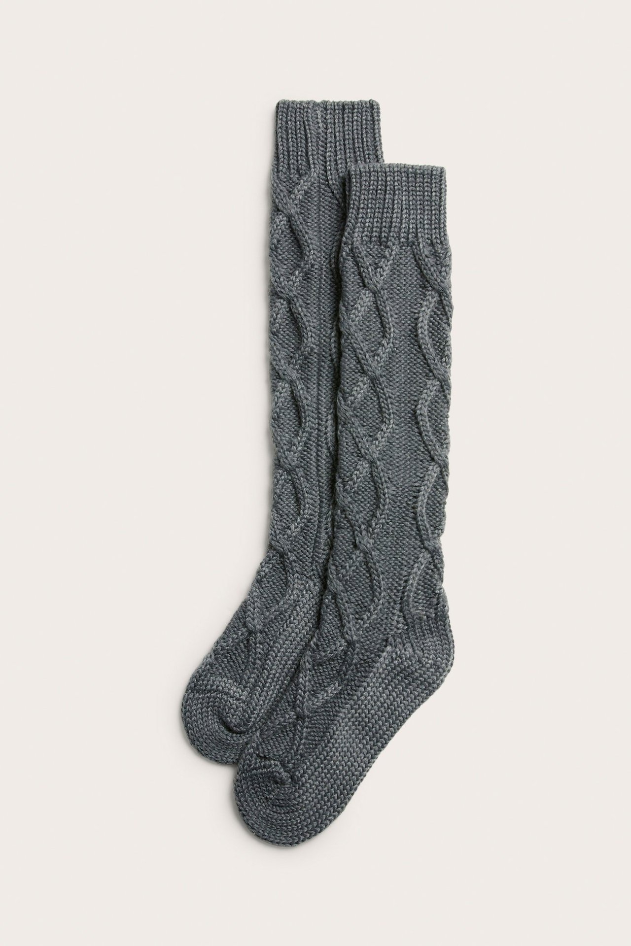 Widok z góry na parę szarych, warkoczowych podkolanówek z grubej przędzy.